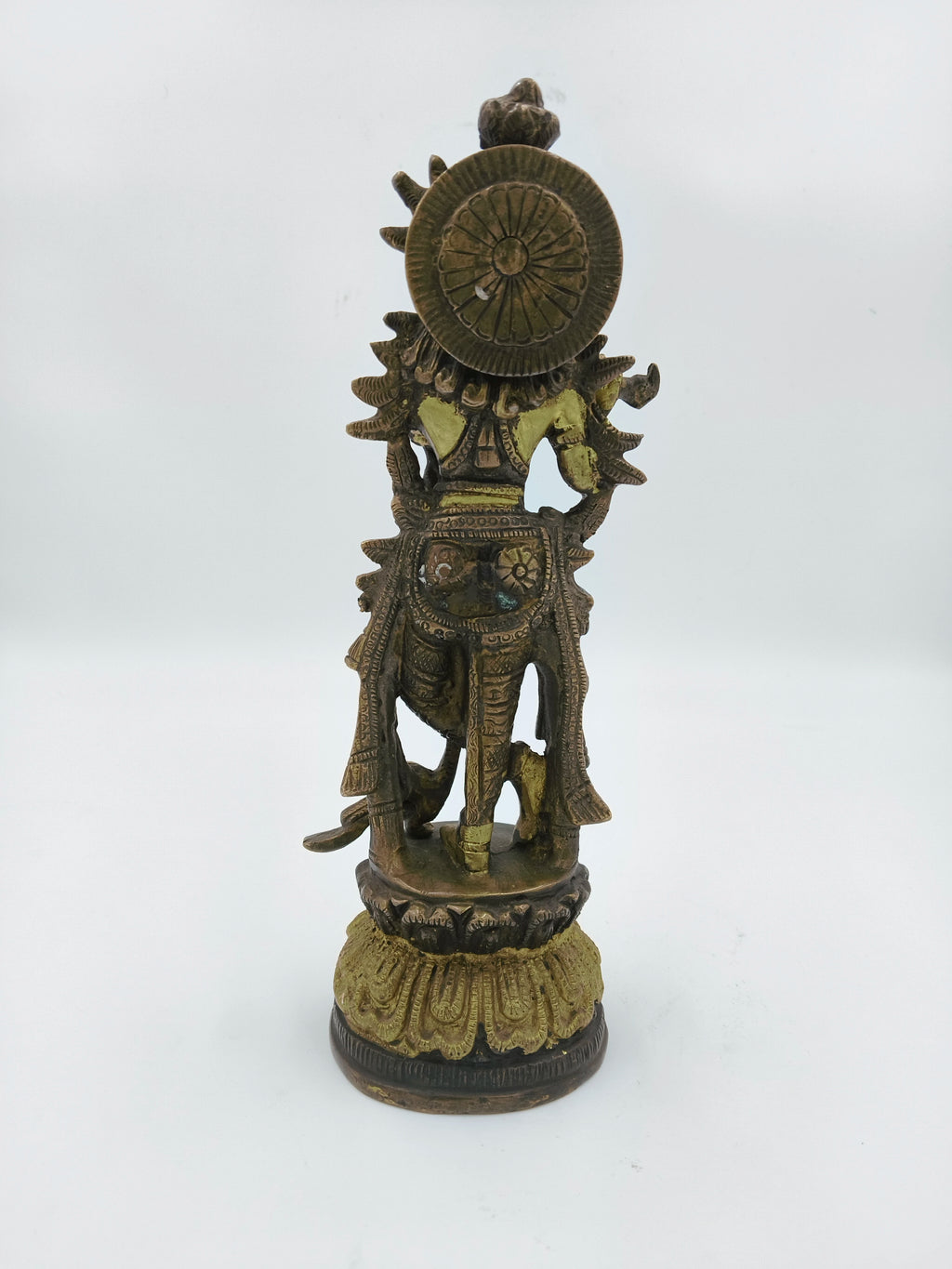 Back view of large brass Krishna statue standing on decorative base