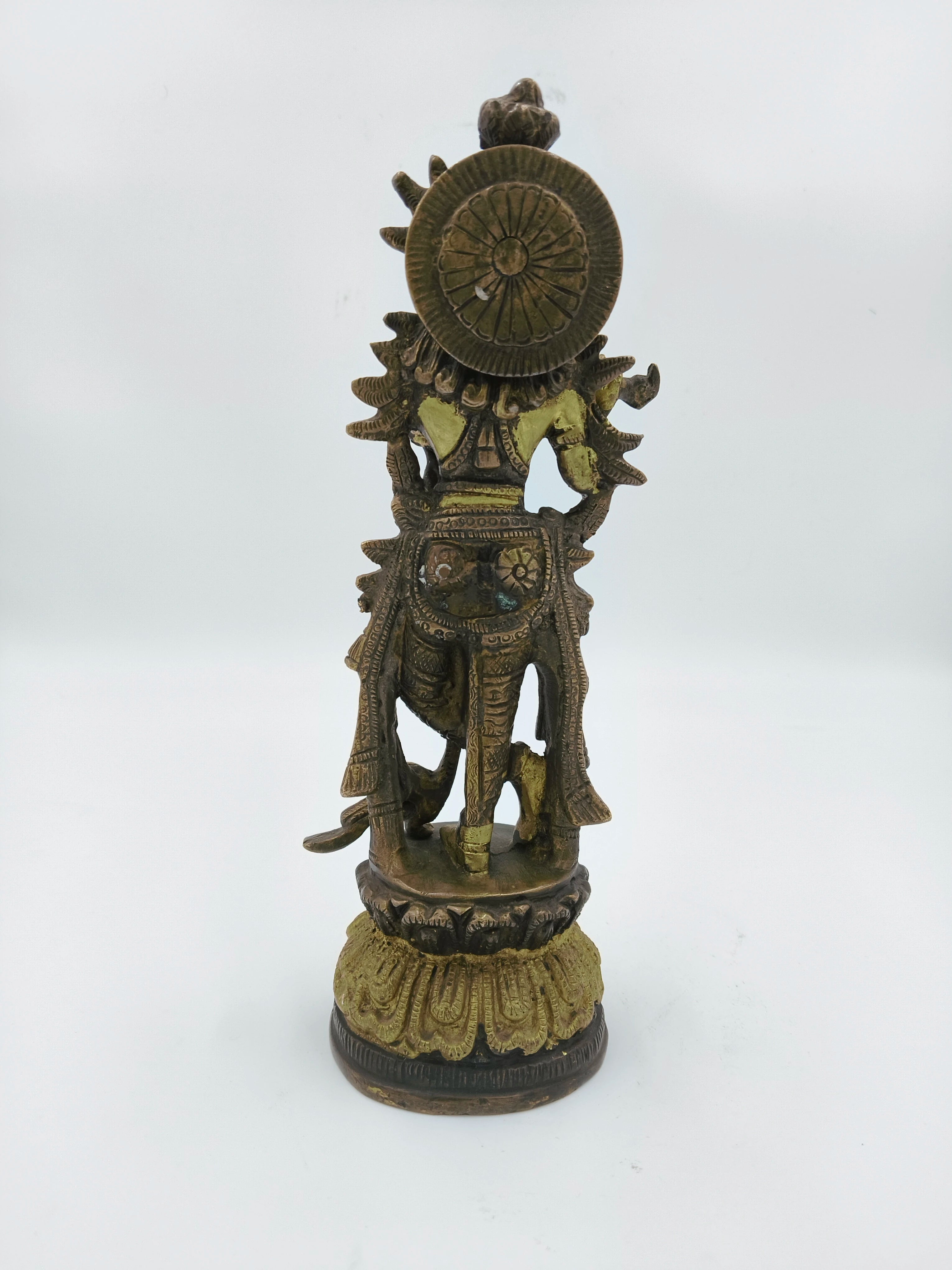 Back view of large brass Krishna statue standing on decorative base
