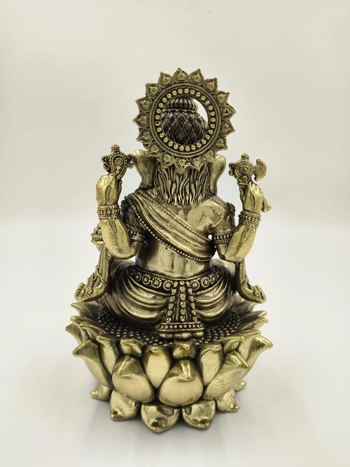 Back view of medium brass Padmasana Ganapati sitting on lotus sculpture