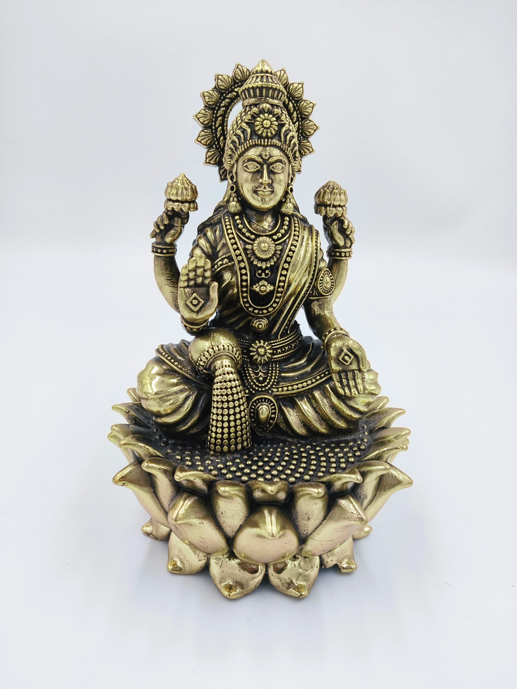 Brass statue of Dhanalakshmi seated on a lotus with four arms holding lotuses