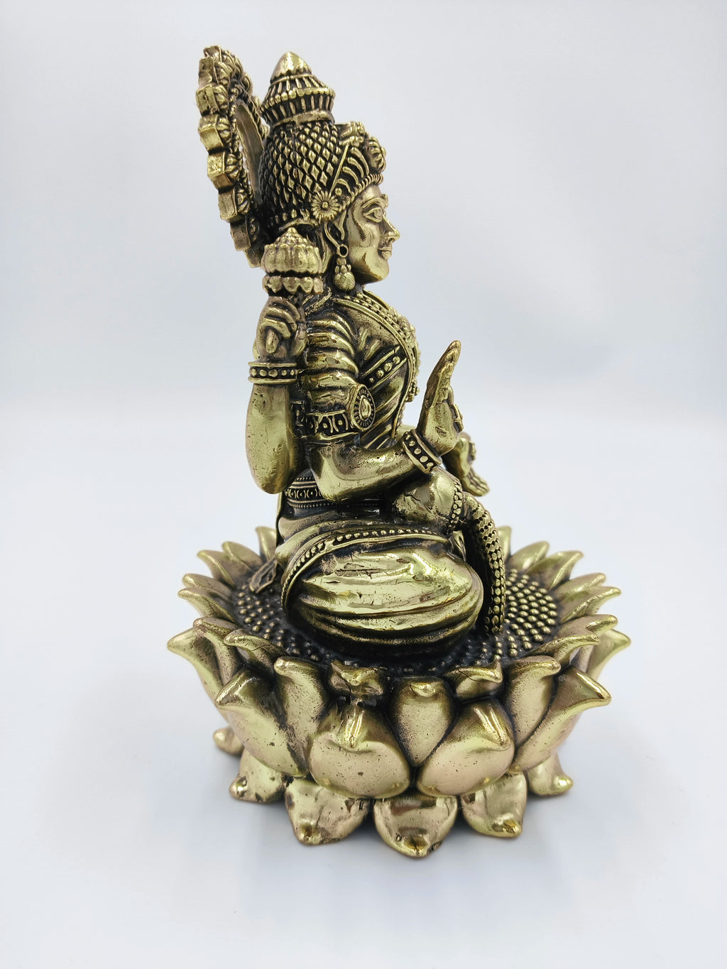 Brass sculpture of Dhanalakshmi deity seated on lotus base side view