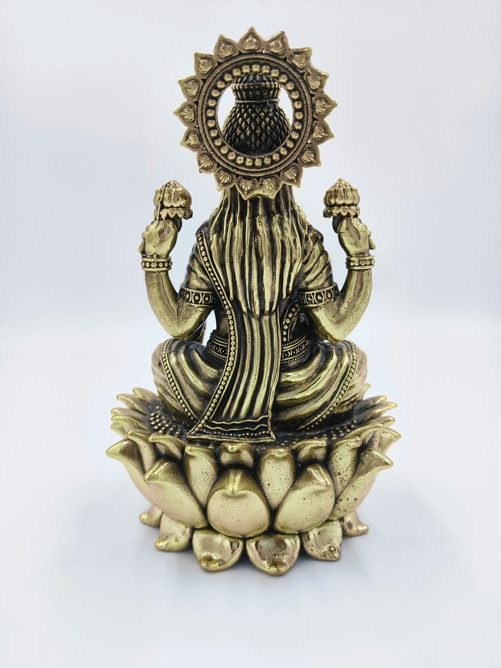 Back view of brass Dhanalakshmi statue seated on a lotus flower base