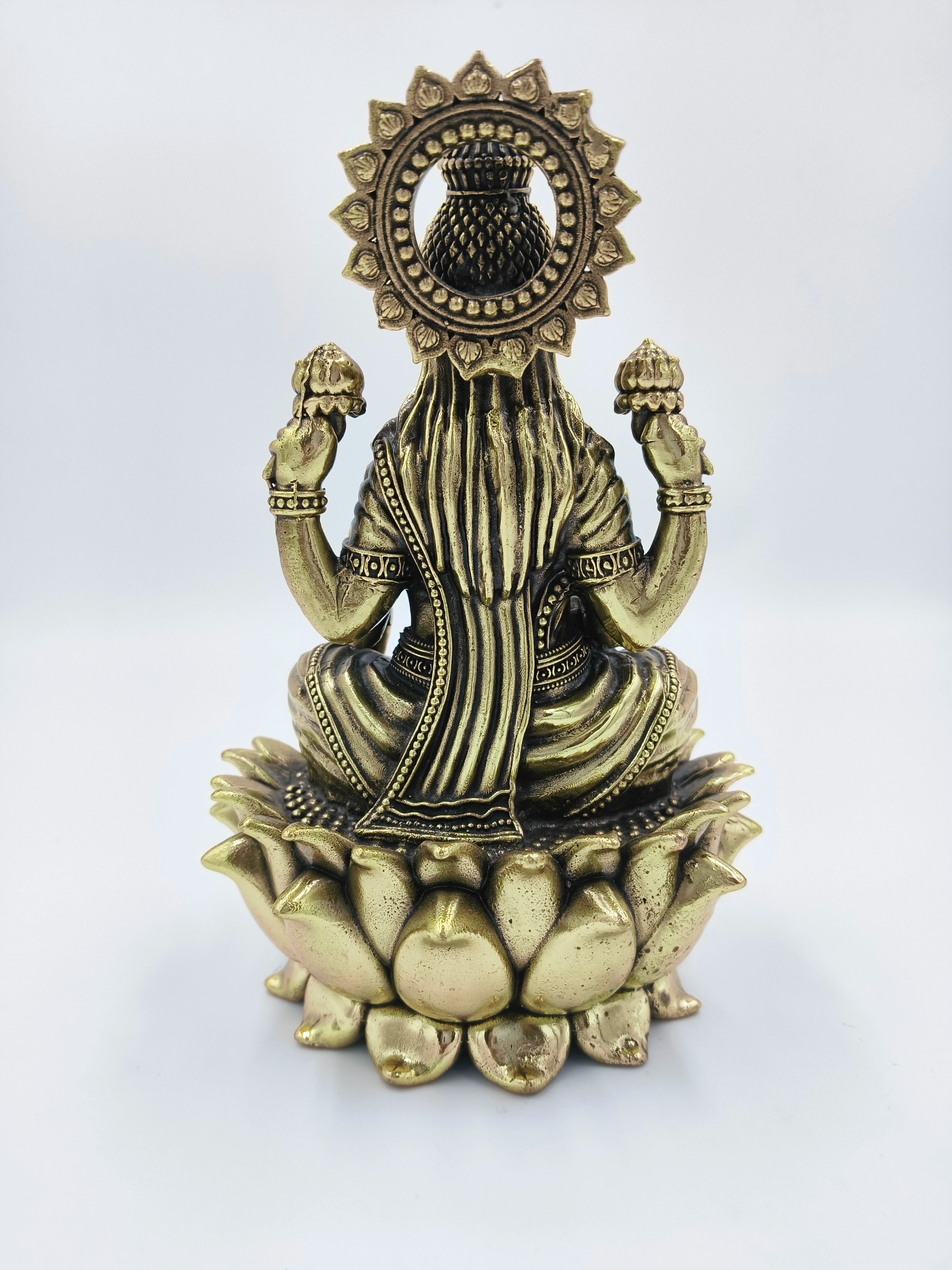 Back view of brass Dhanalakshmi statue seated on a lotus flower base