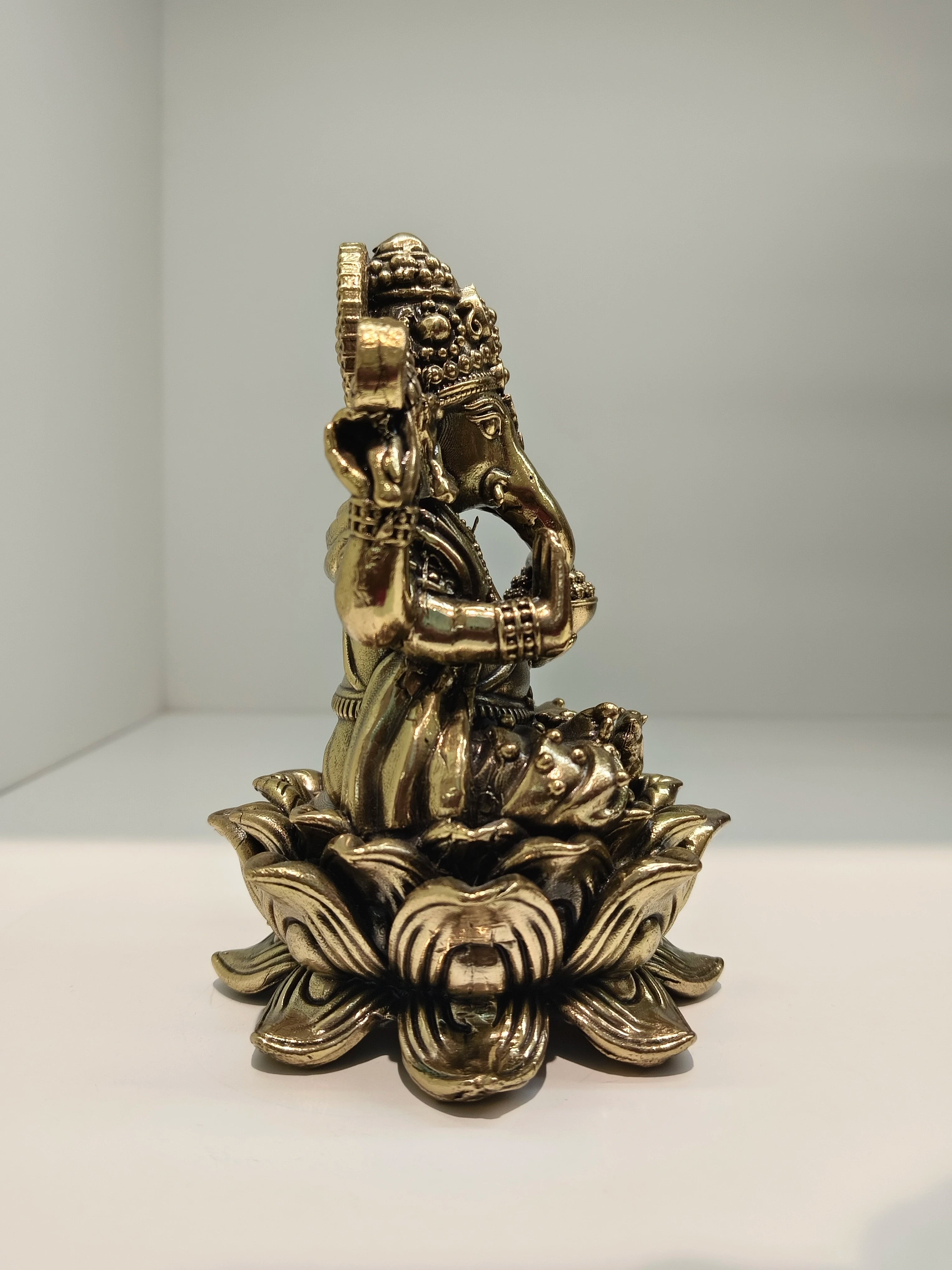 Side view of mini brass Padmasana Ganapati statue seated on a lotus base