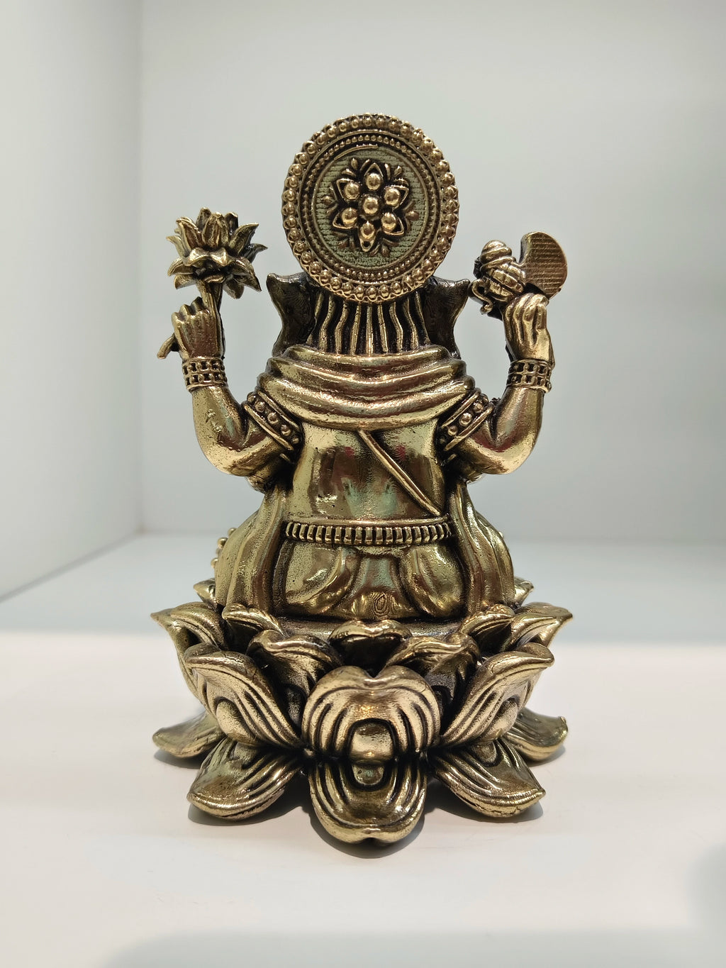 Back view of mini brass Padmasana Ganapati statue seated on a lotus base