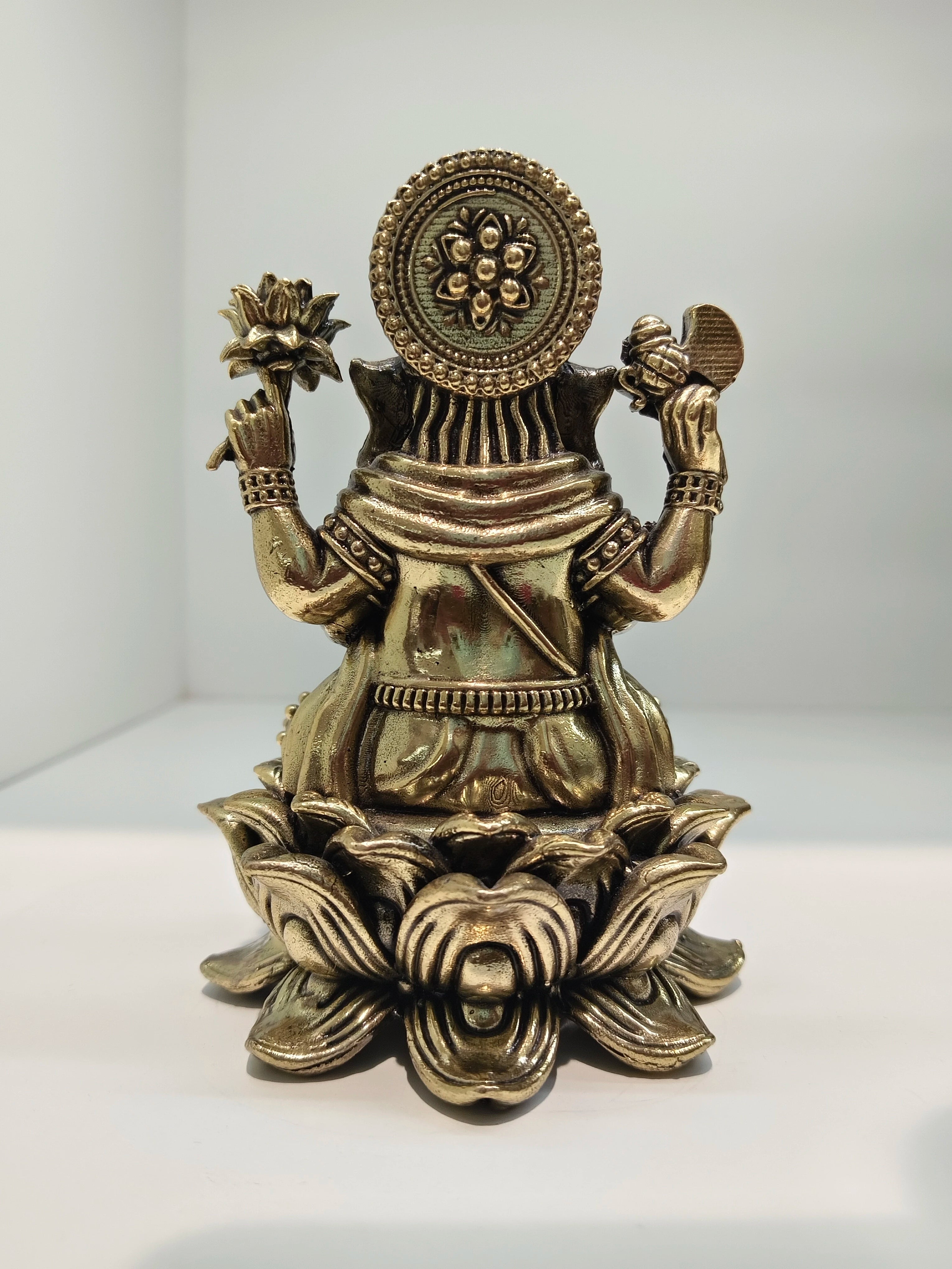 Back view of mini brass Padmasana Ganapati statue seated on a lotus base