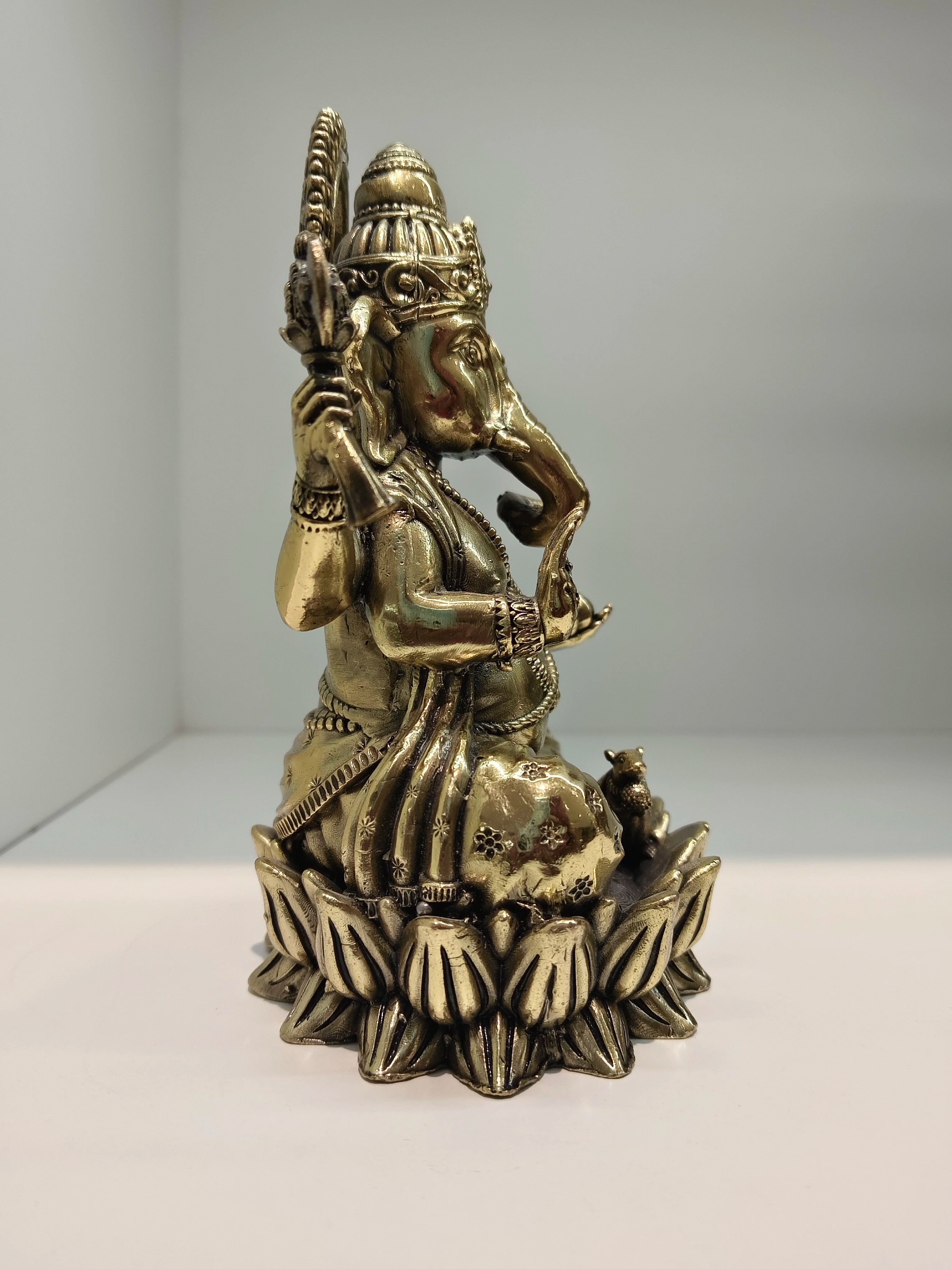 Medium brass statue of Ganesh seated in Padmasana lotus posture side view