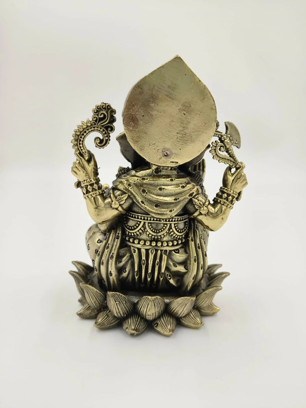 Back view of a brass Ganesh statue sitting on a lotus flower base