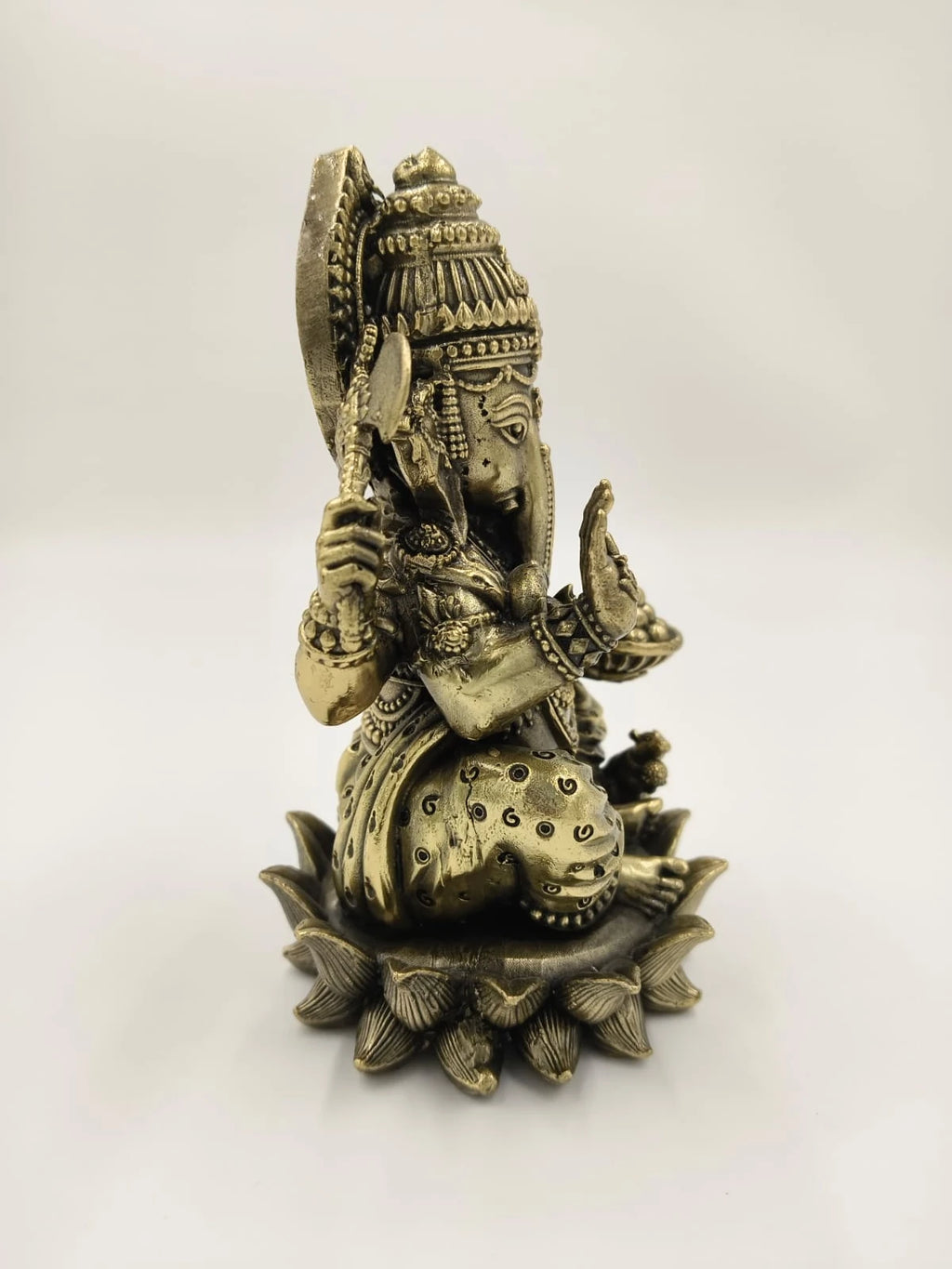 Side view of medium brass Ganesh sitting on detailed lotus base sculpture