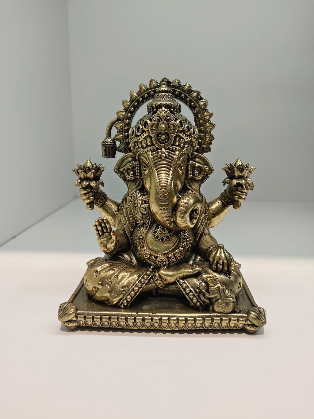 Small brass Padma Hasta Ganapati statue seated on decorative base