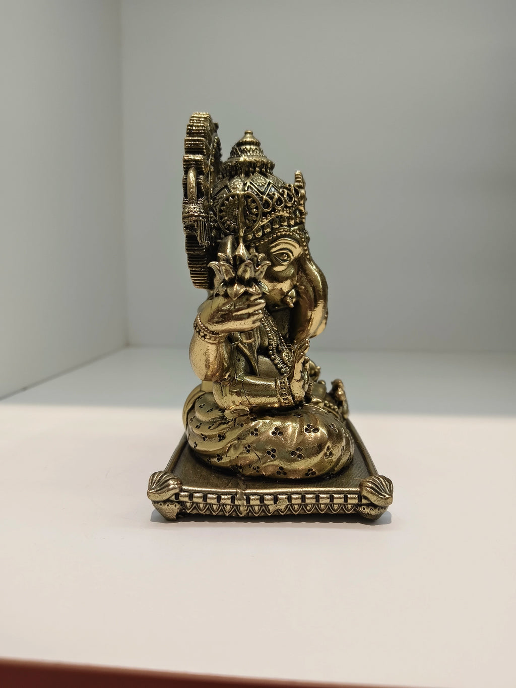 Small brass Padma Hasta Ganapati statue side view on ornate base