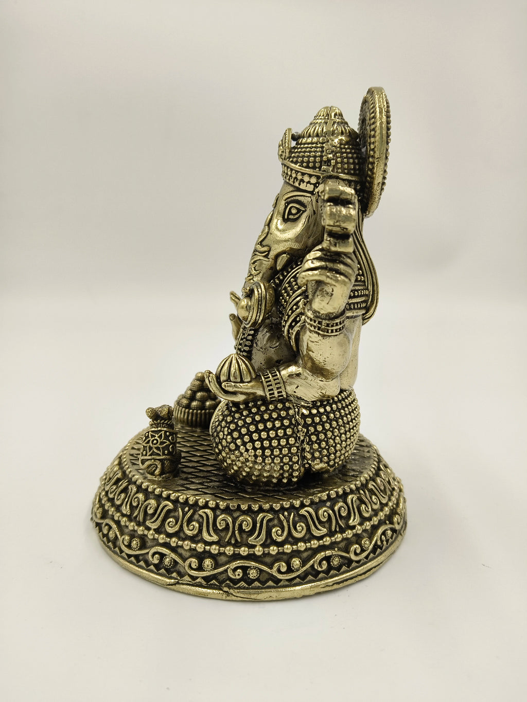 Side view of brass Padma Hasta Ganapati statue with detailed base