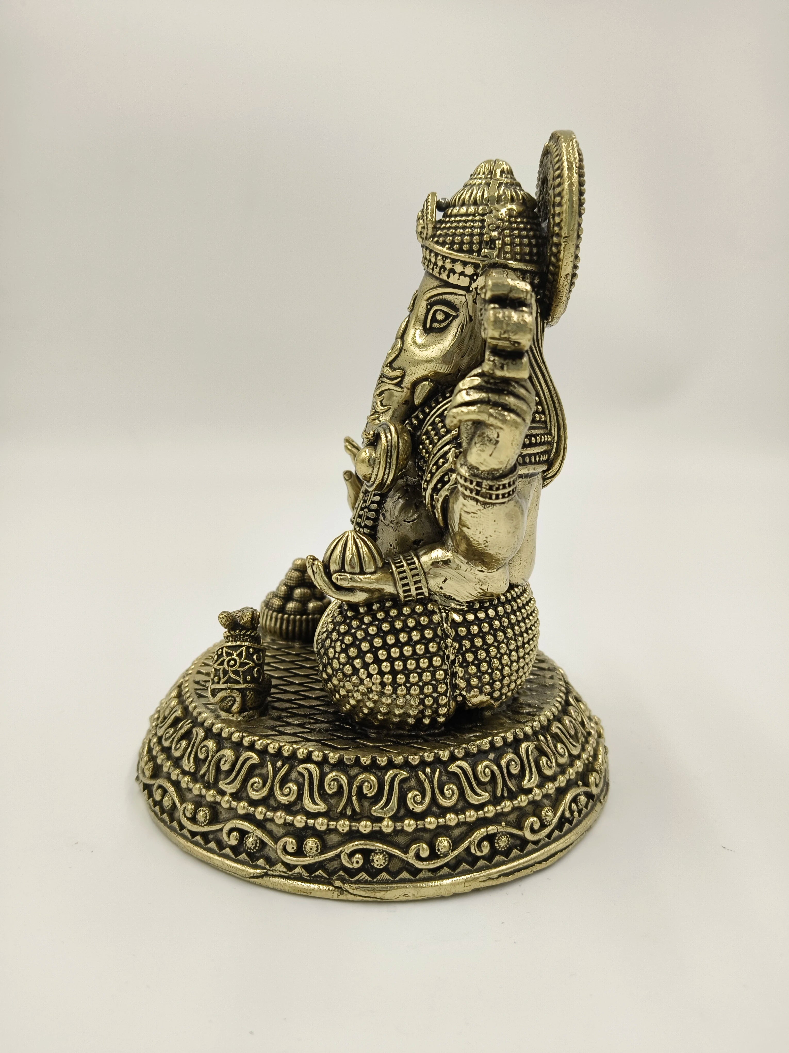 Side view of brass Padma Hasta Ganapati statue with detailed base