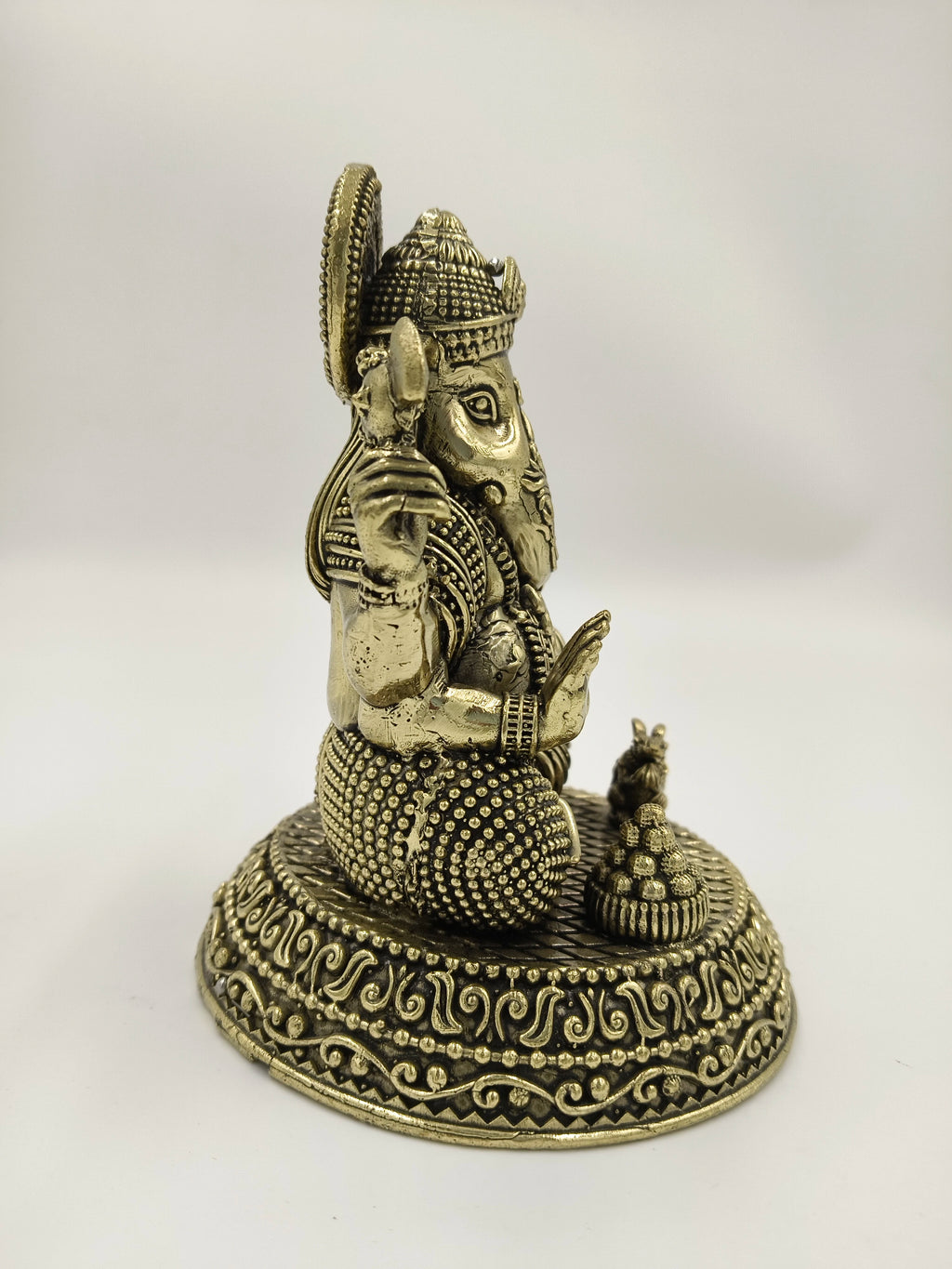 Side view of brass Padma Hasta Ganapati sculpture on decorated base