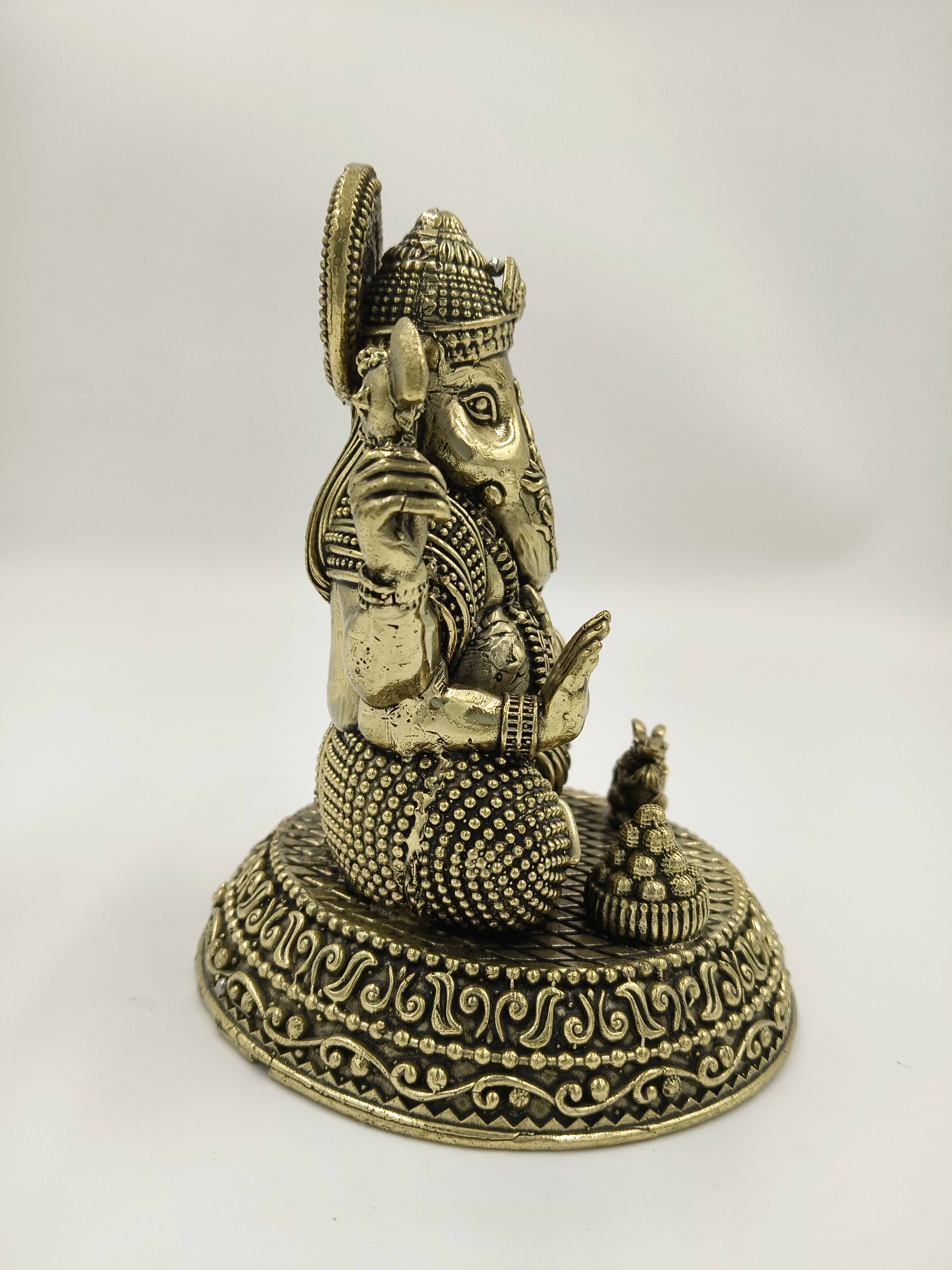 Side view of brass Padma Hasta Ganapati sculpture on decorated base