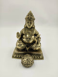 Medium brass Kubera statue seated with a spherical ornament in front
