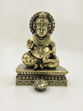 Small brass Kubera sculpture seated on ornate pedestal with pot in front