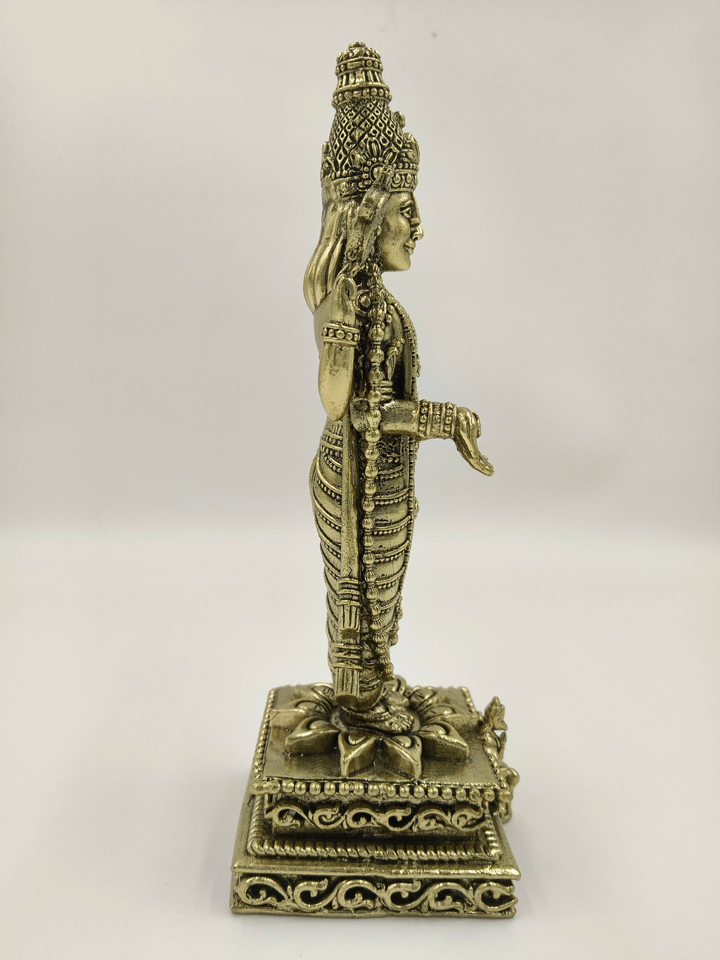 Side view of a large brass Balaji sculpture standing on an ornate pedestal