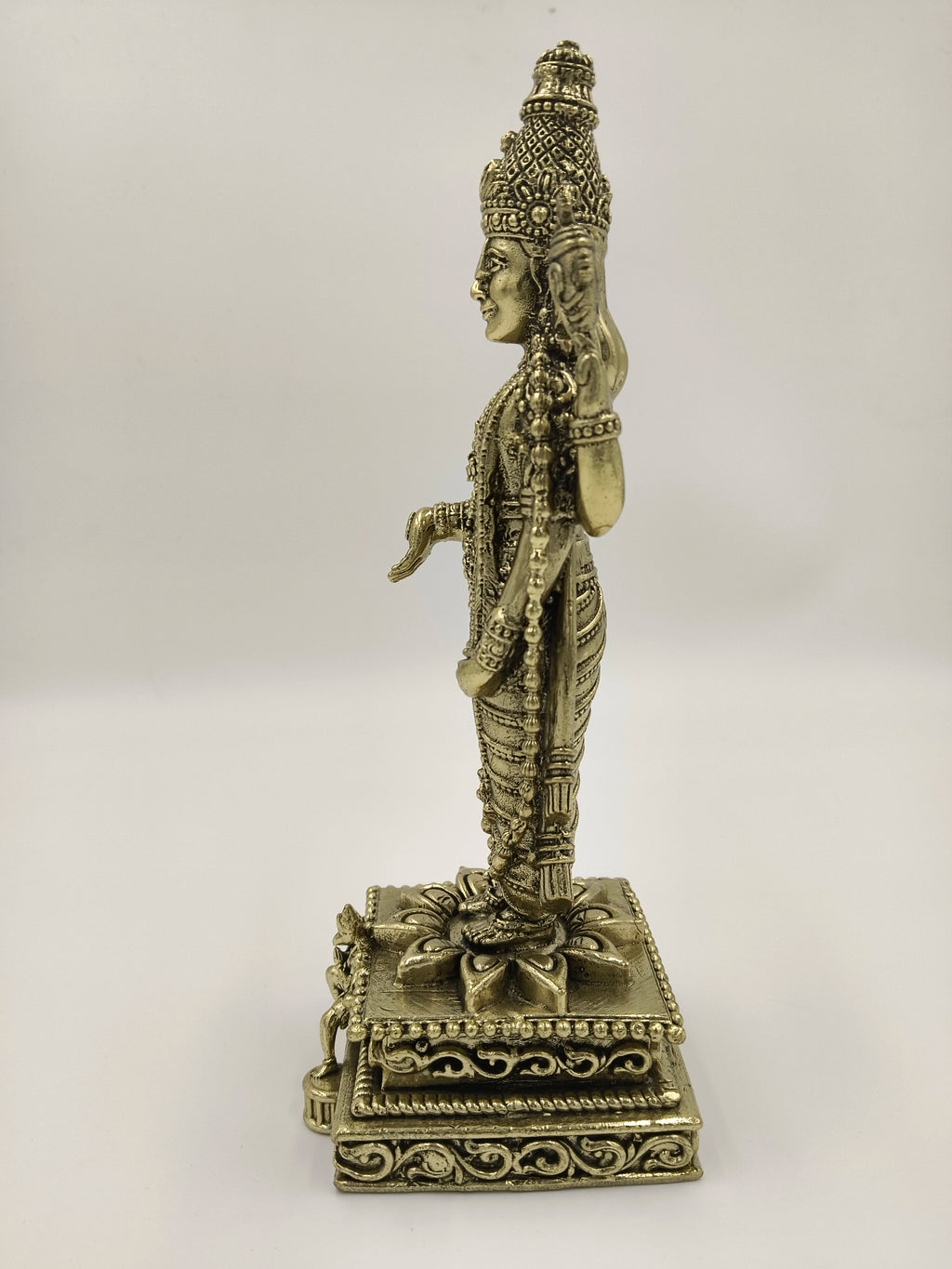 Side view of large brass Balaji sculpture with detailed carvings on base