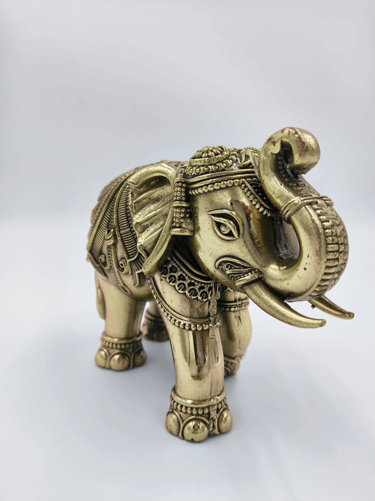 Ornate small brass elephant sculpture with decorative engravings, side view