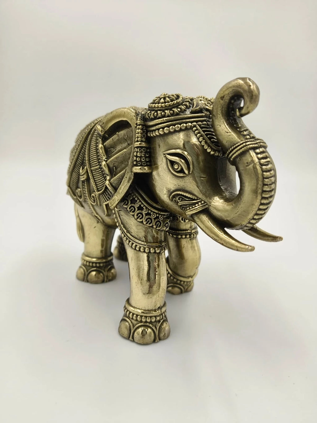 Small brass elephant sculpture with detailed engravings and raised trunk
