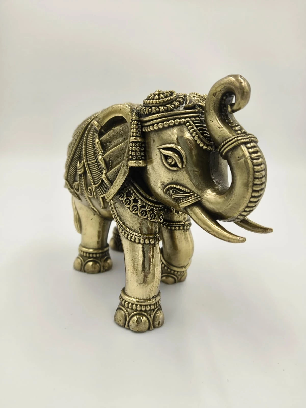 Small brass elephant sculpture with detailed engravings and raised trunk
