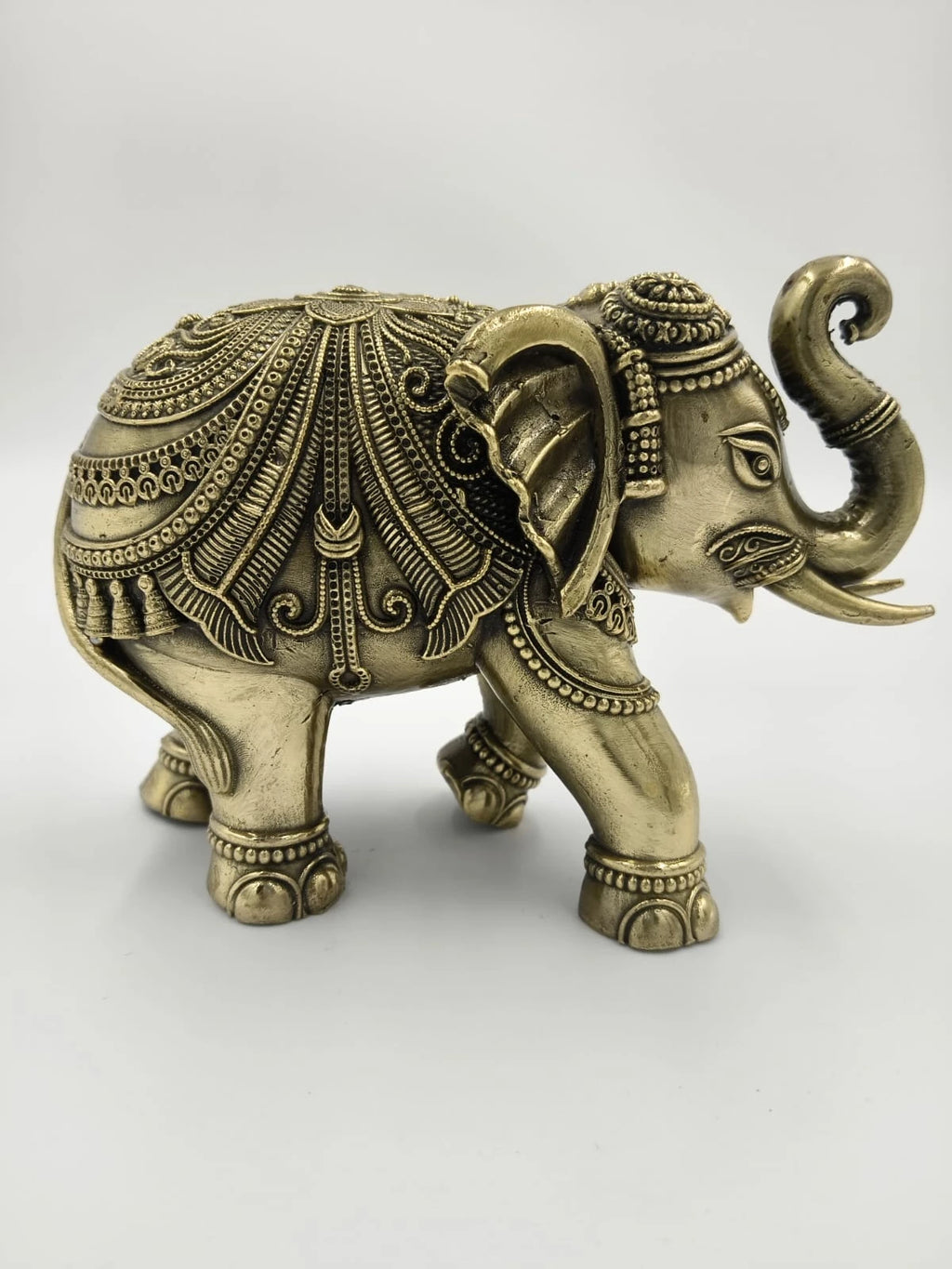Small brass elephant figurine with intricate detailed patterns, side view