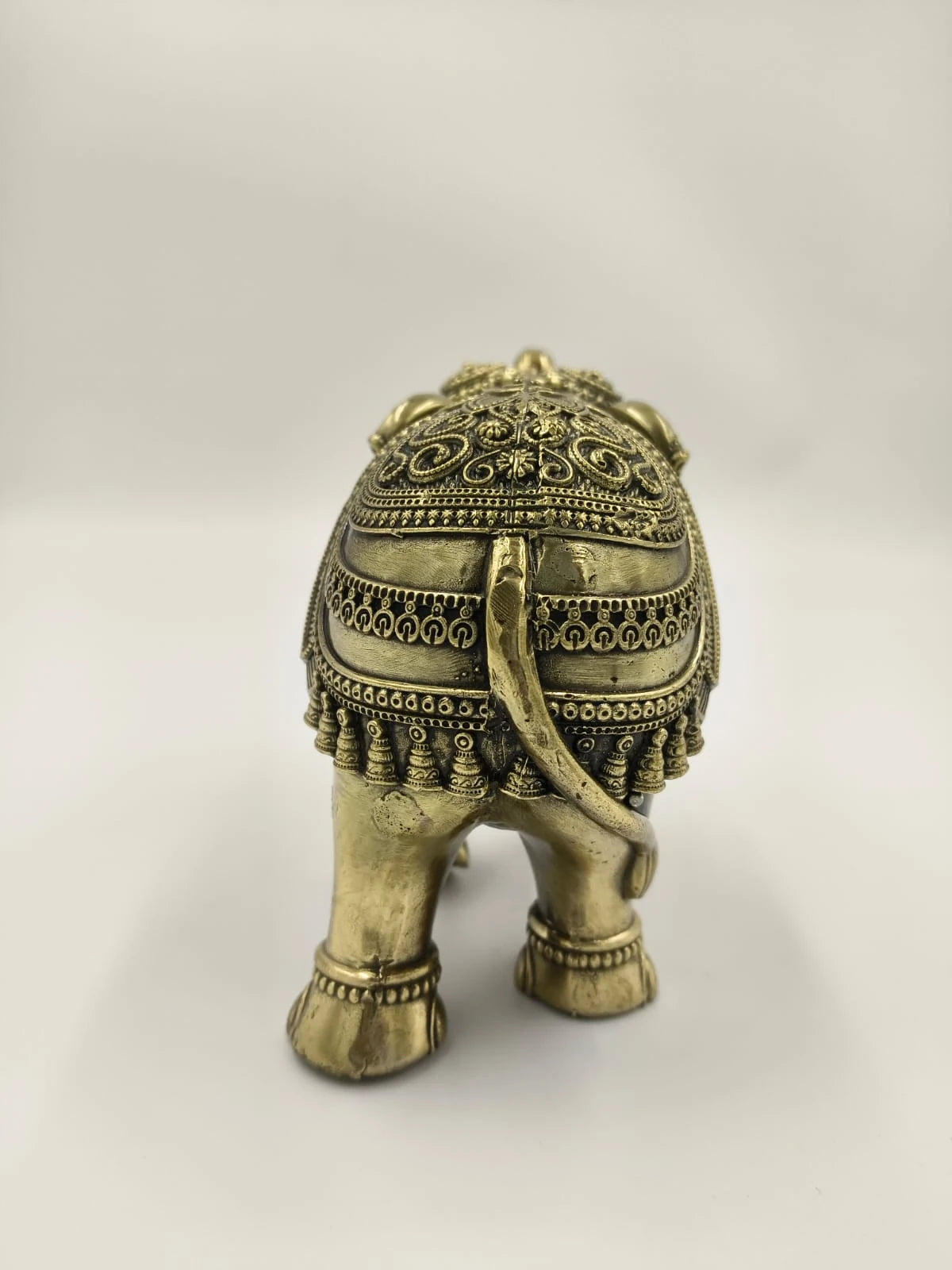 Small brass elephant sculpture with detailed ornamental patterns rear view