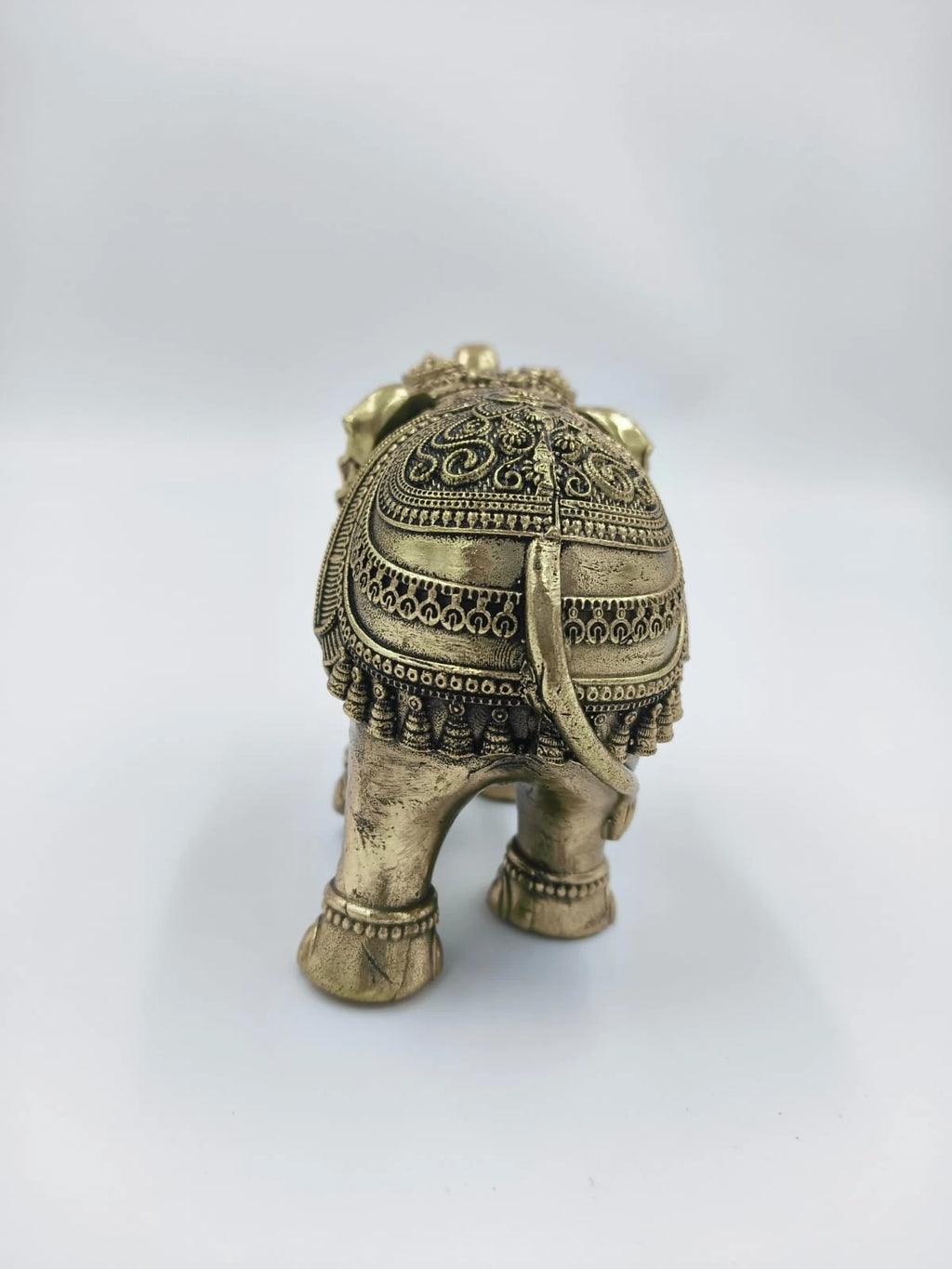 Rear view of small brass elephant figurine with intricate carvings