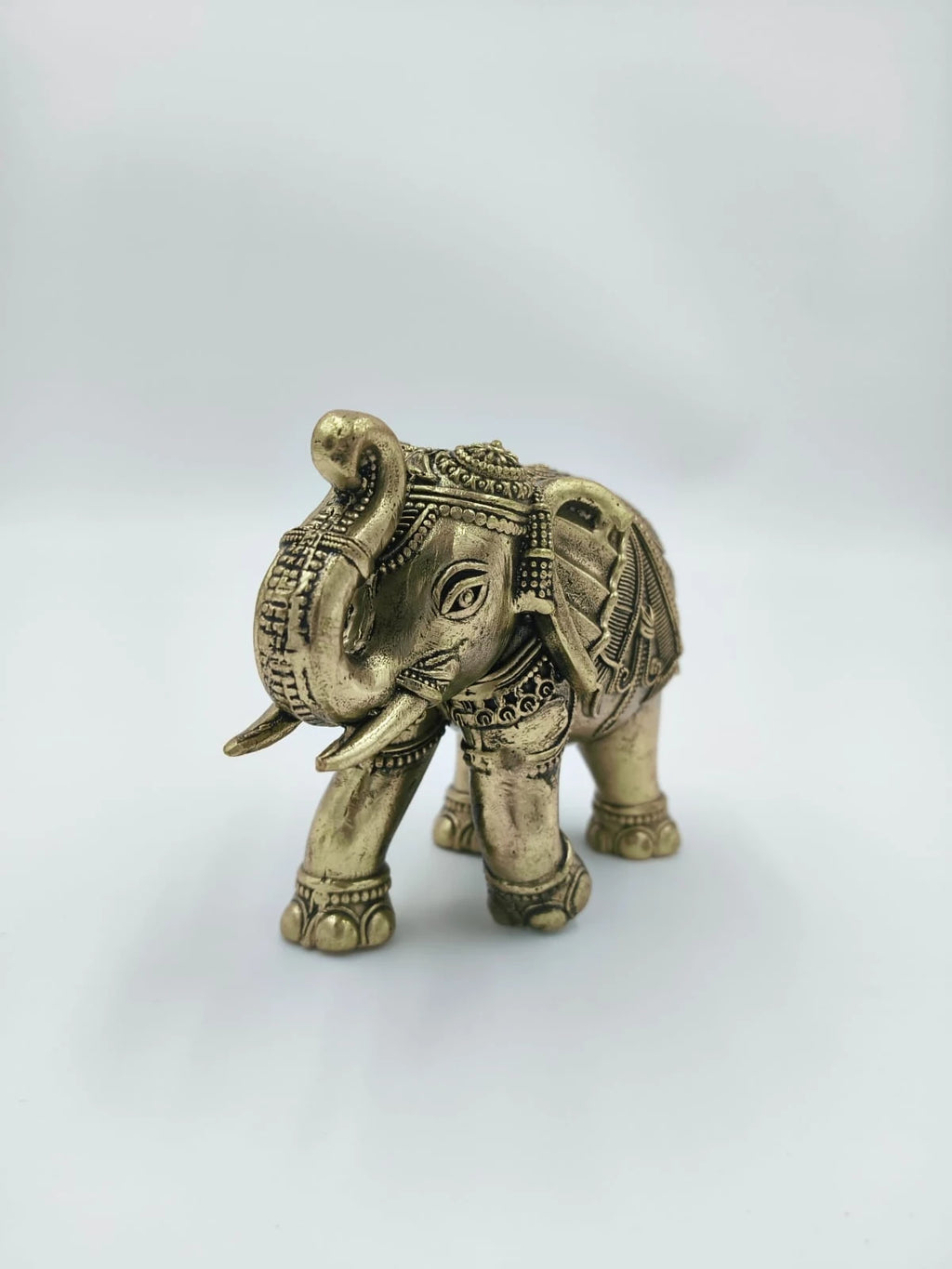 Small brass elephant figurine with intricate decorative patterns, front view