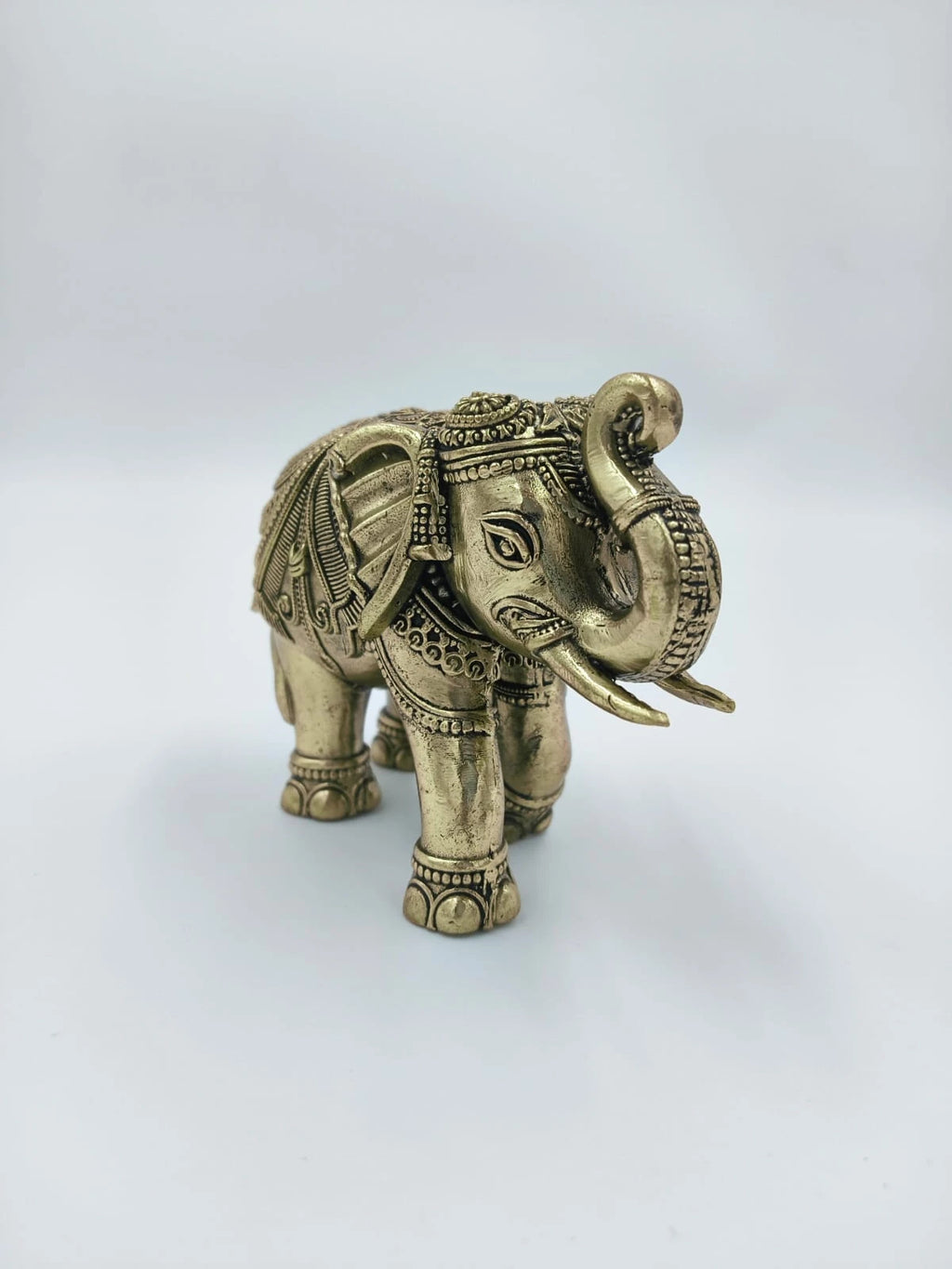 small brass elephant sculpture with intricate carvings and raised trunk