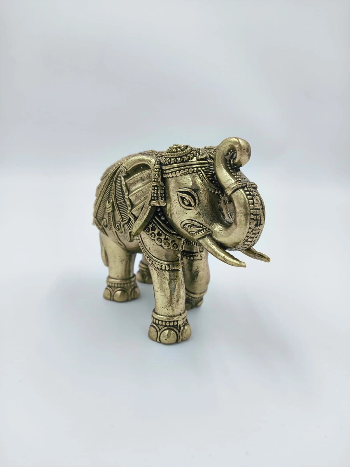 small brass elephant sculpture with intricate carvings and raised trunk