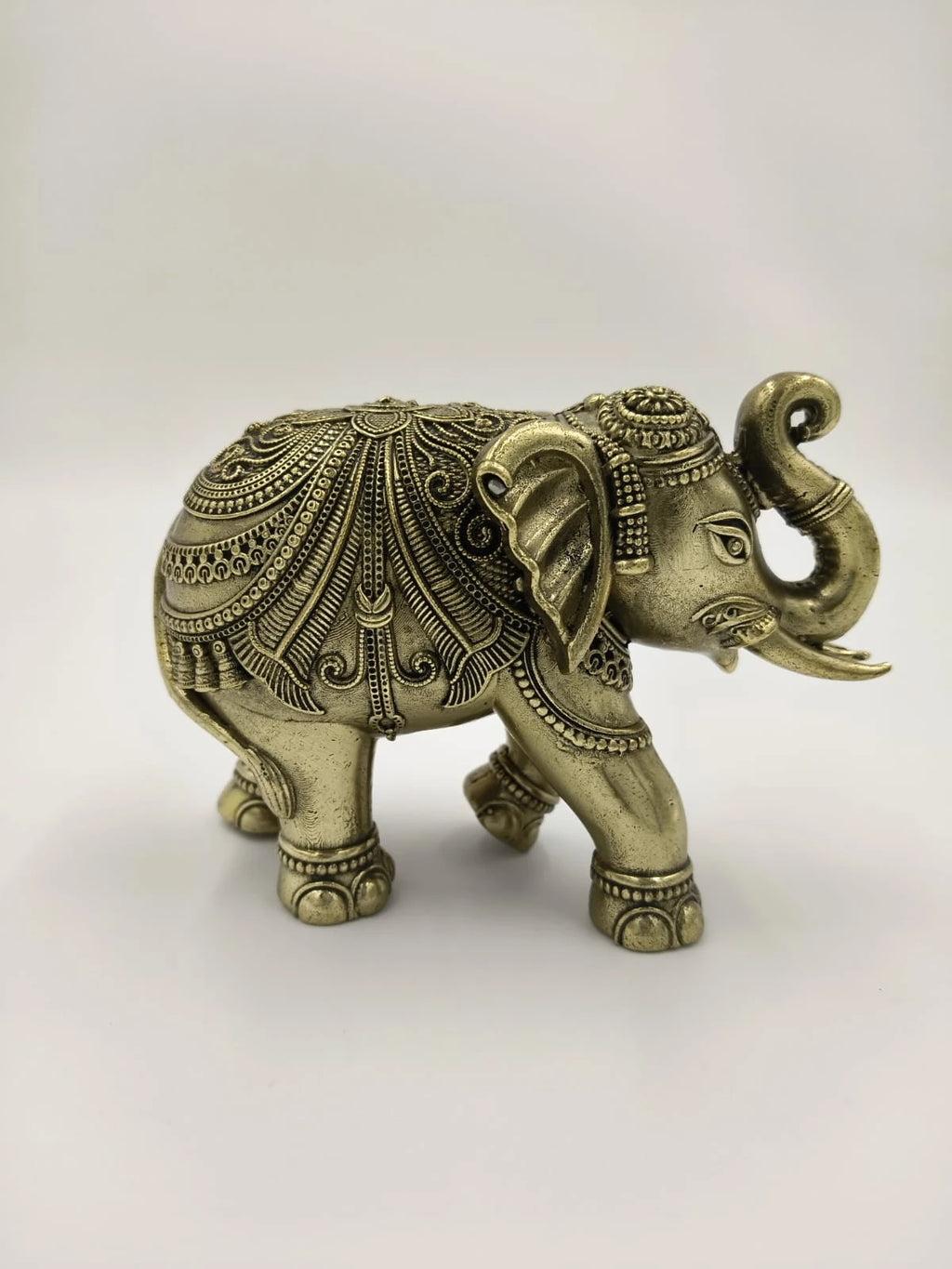 Small brass elephant figurine with intricate detailed engravings side view