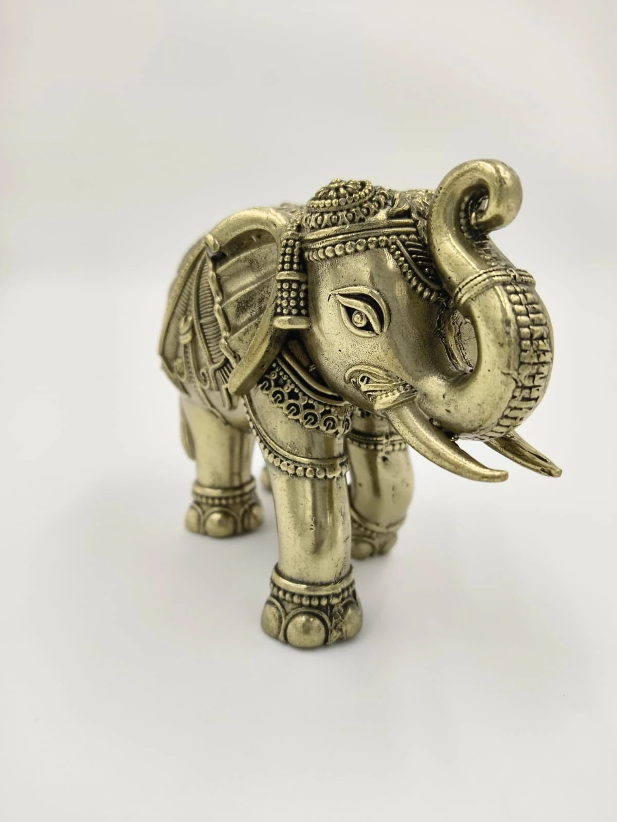 Small brass elephant figurine with ornate detailing and raised trunk