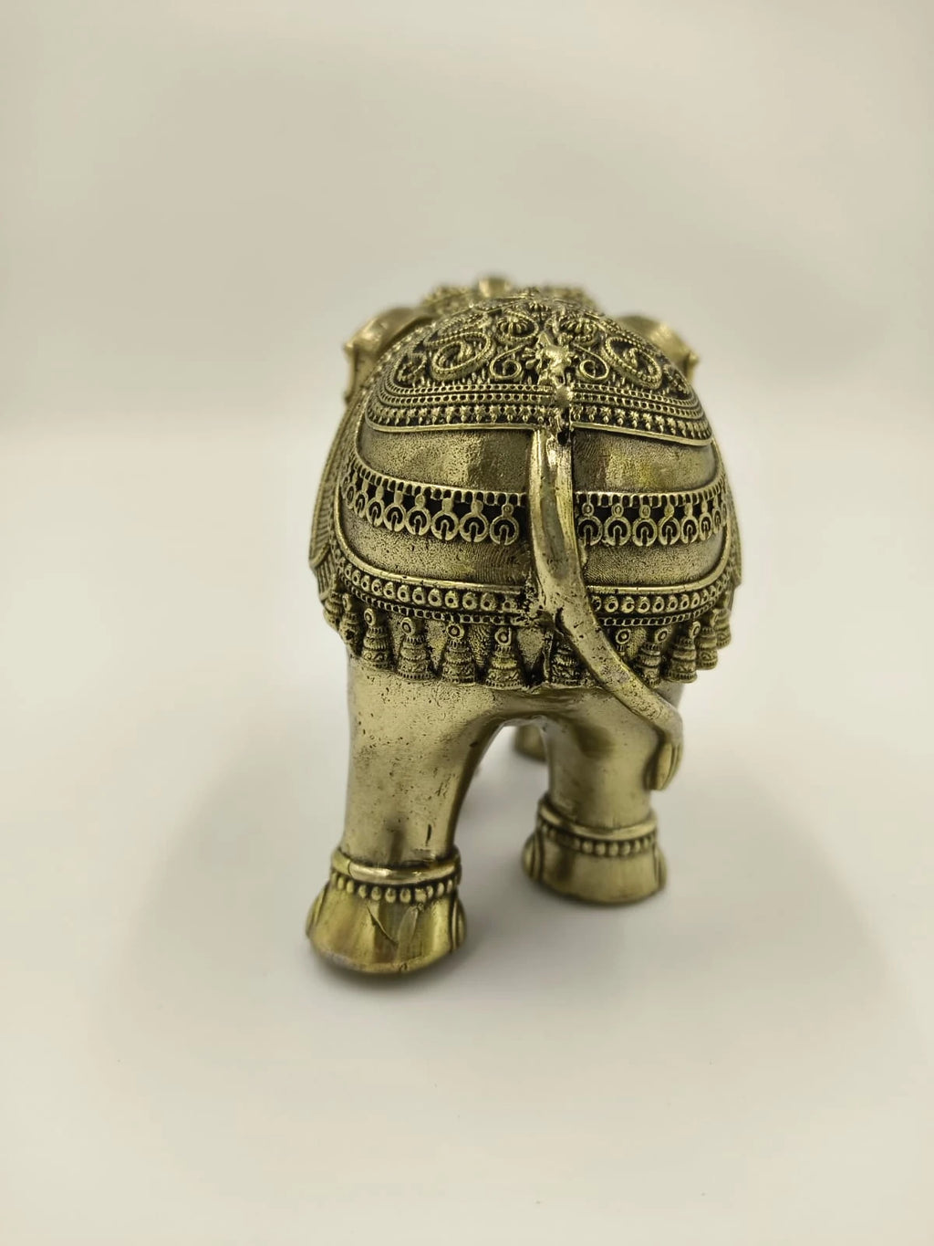 Rear view of small brass elephant figurine with intricate carved details