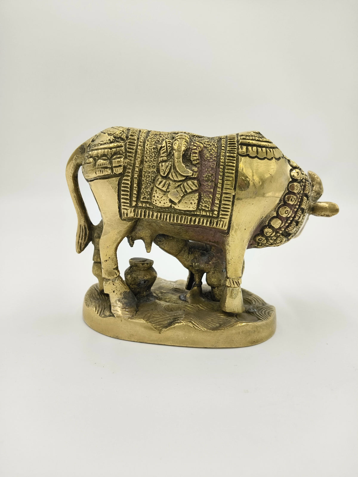 Brass sculpture of a cow and calf with carved Ganesha motif on blanket