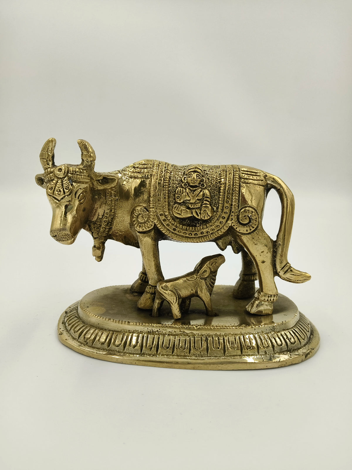 Small brass figurine of a cow with calf on decorative base
