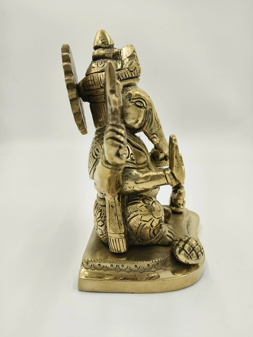 Side view of large brass Raja Ganapati statue with detailed carvings