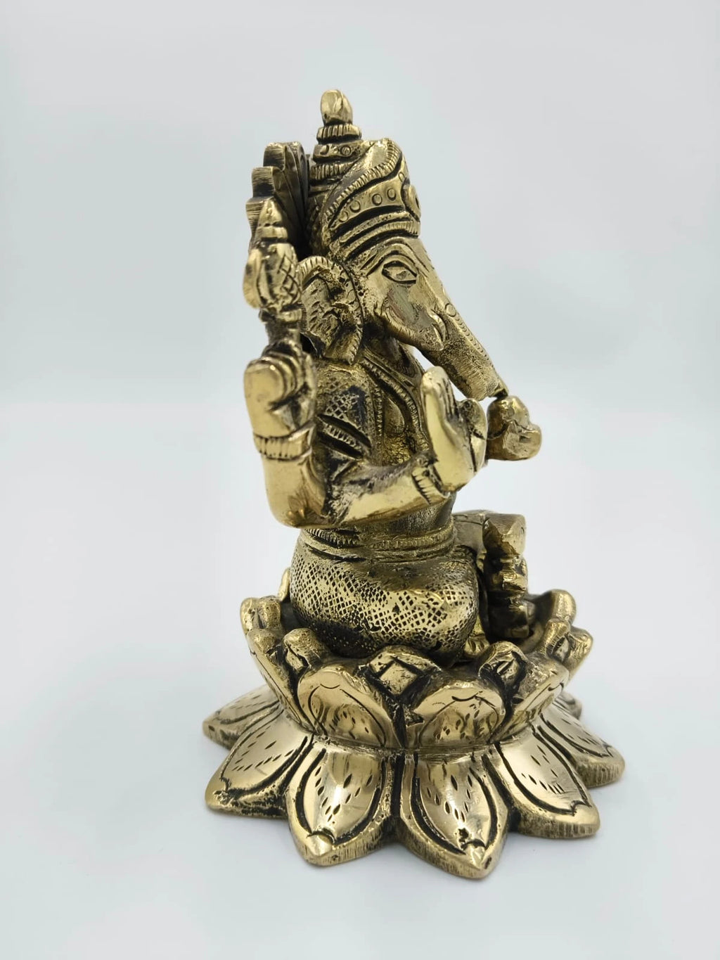 Side view of brass Padma Hasta Ganapati sculpture seated on a lotus pedestal