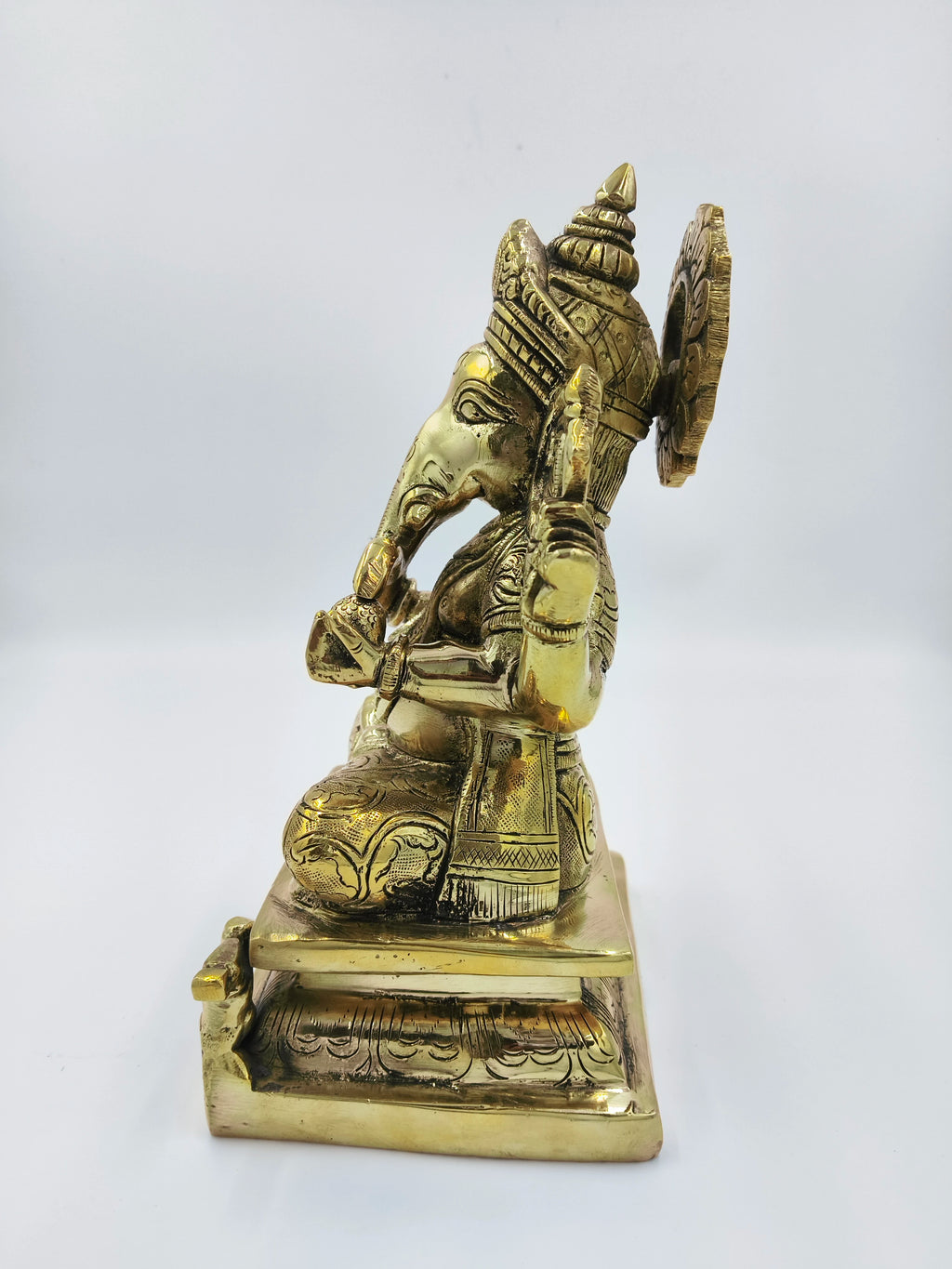Side view of large brass Padmasana Ganapati statue with intricate detailing