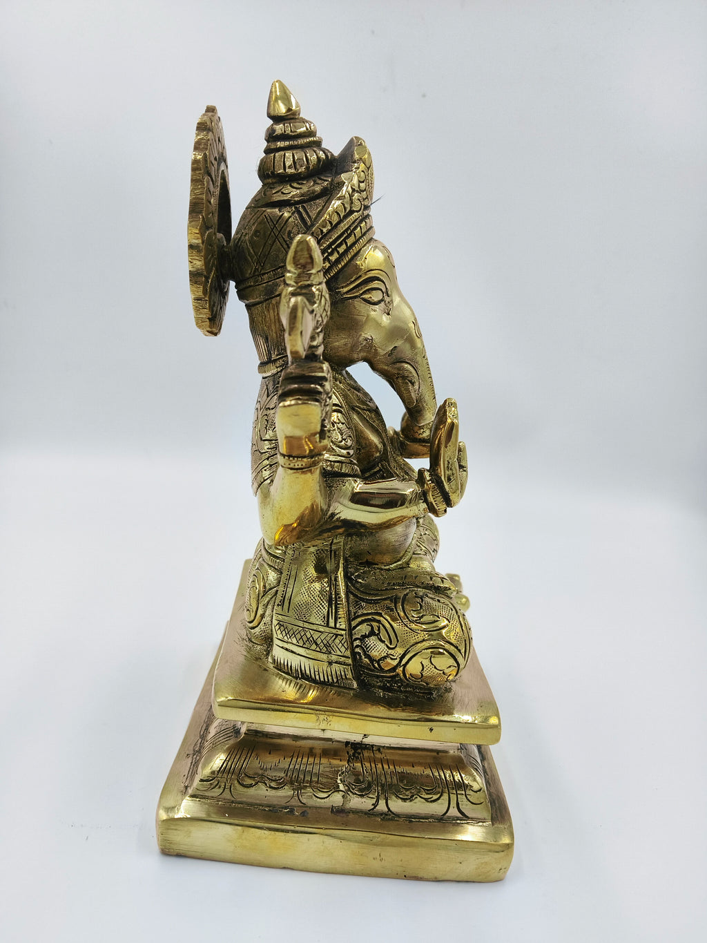 Side view of large brass Padmasana Ganapati statue with intricate detailing