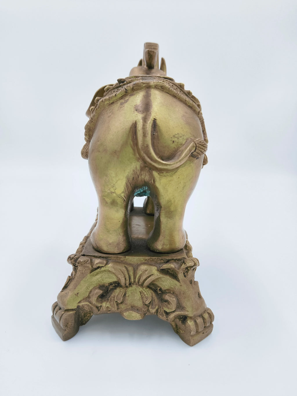 Rear view of large brass elephant sculpture on ornate base