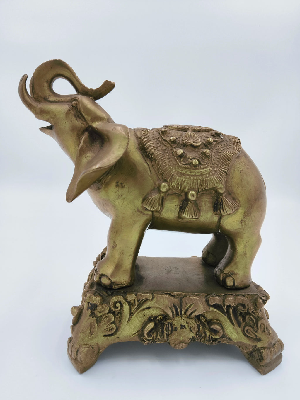 Large brass elephant sculpture with intricate saddle details on decorative base