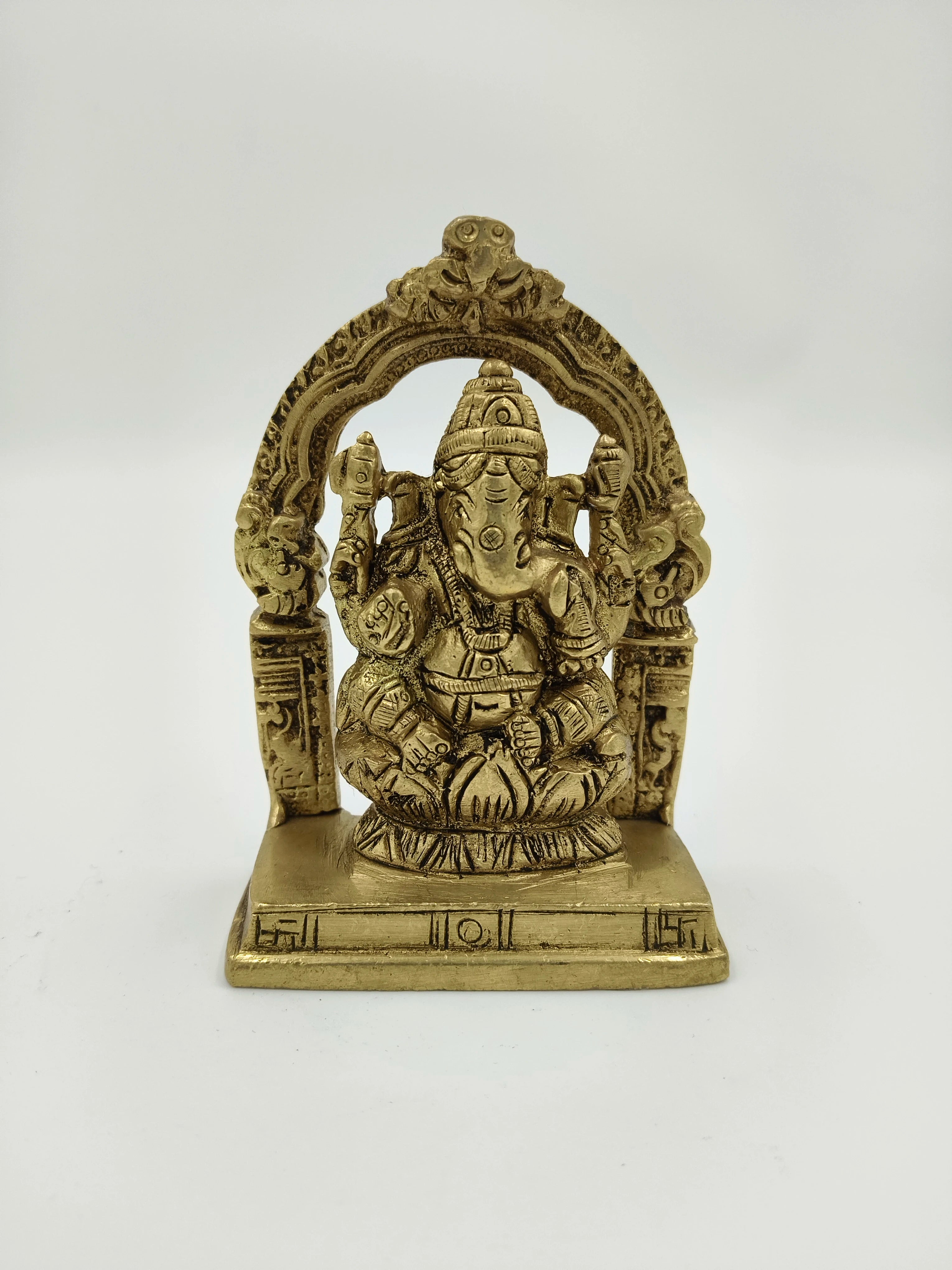 Small brass sculpture of Lord Ganesha seated with decorative arch on base