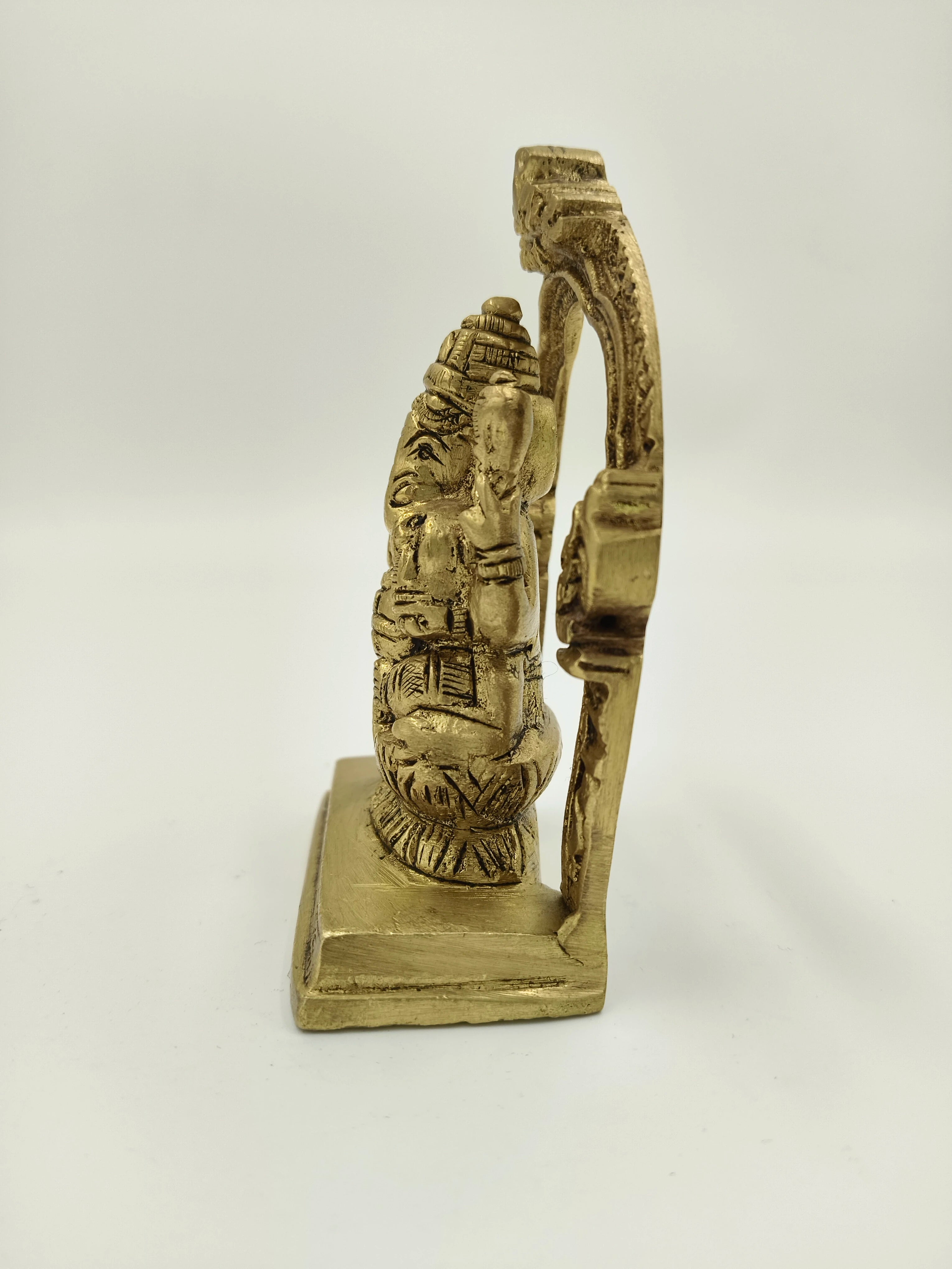 Side view of small brass Ganesha sculpture with ornate arch on square base