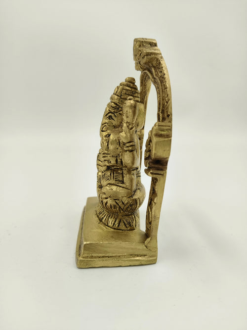 Side view of small brass Ganesha sculpture with ornate arch on square base