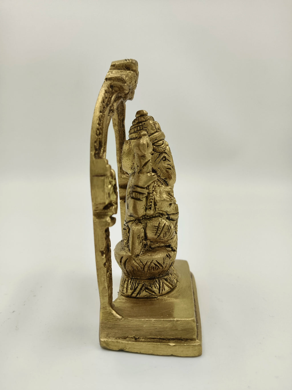 Side view of small brass Lord Ganesha sculpture with decorative arch