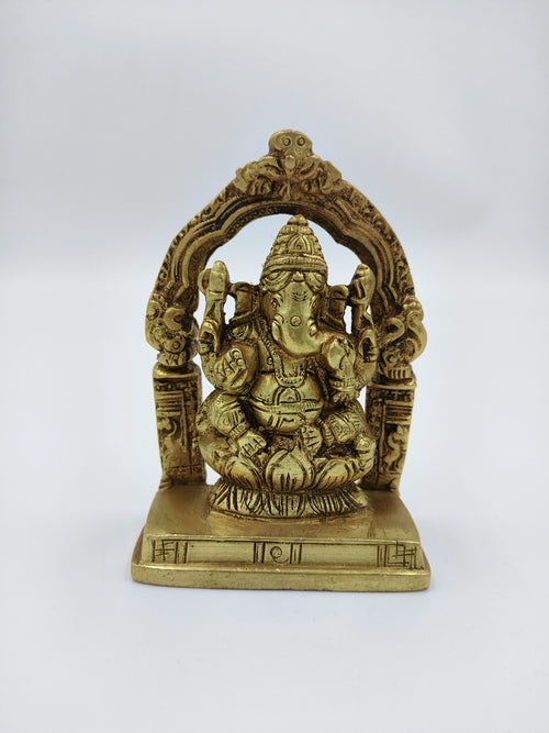 Small brass Lord Ganesh sculpture seated under an ornate arch on a square base
