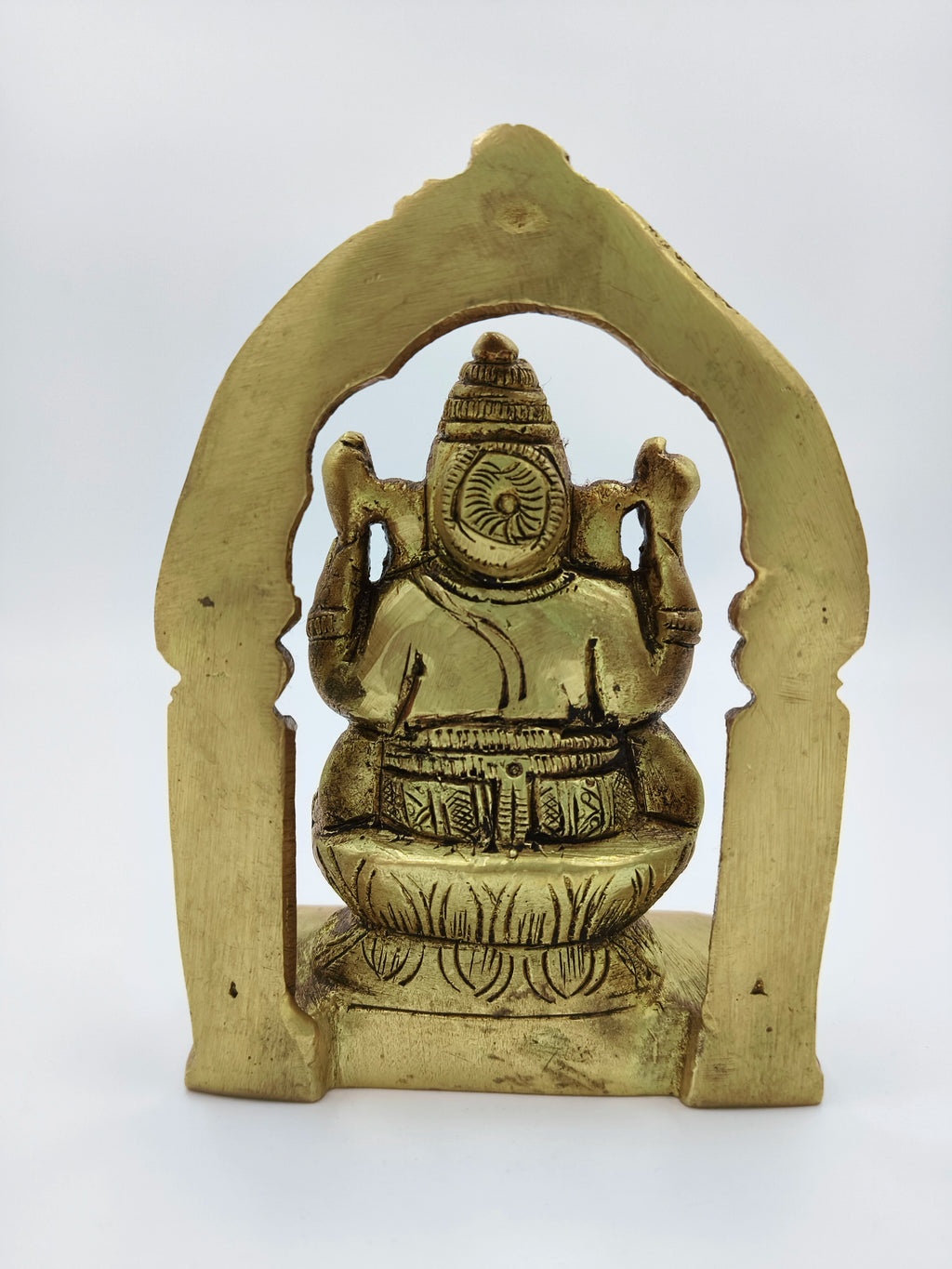 Small brass Ganesh statue viewed from the back within an arch frame
