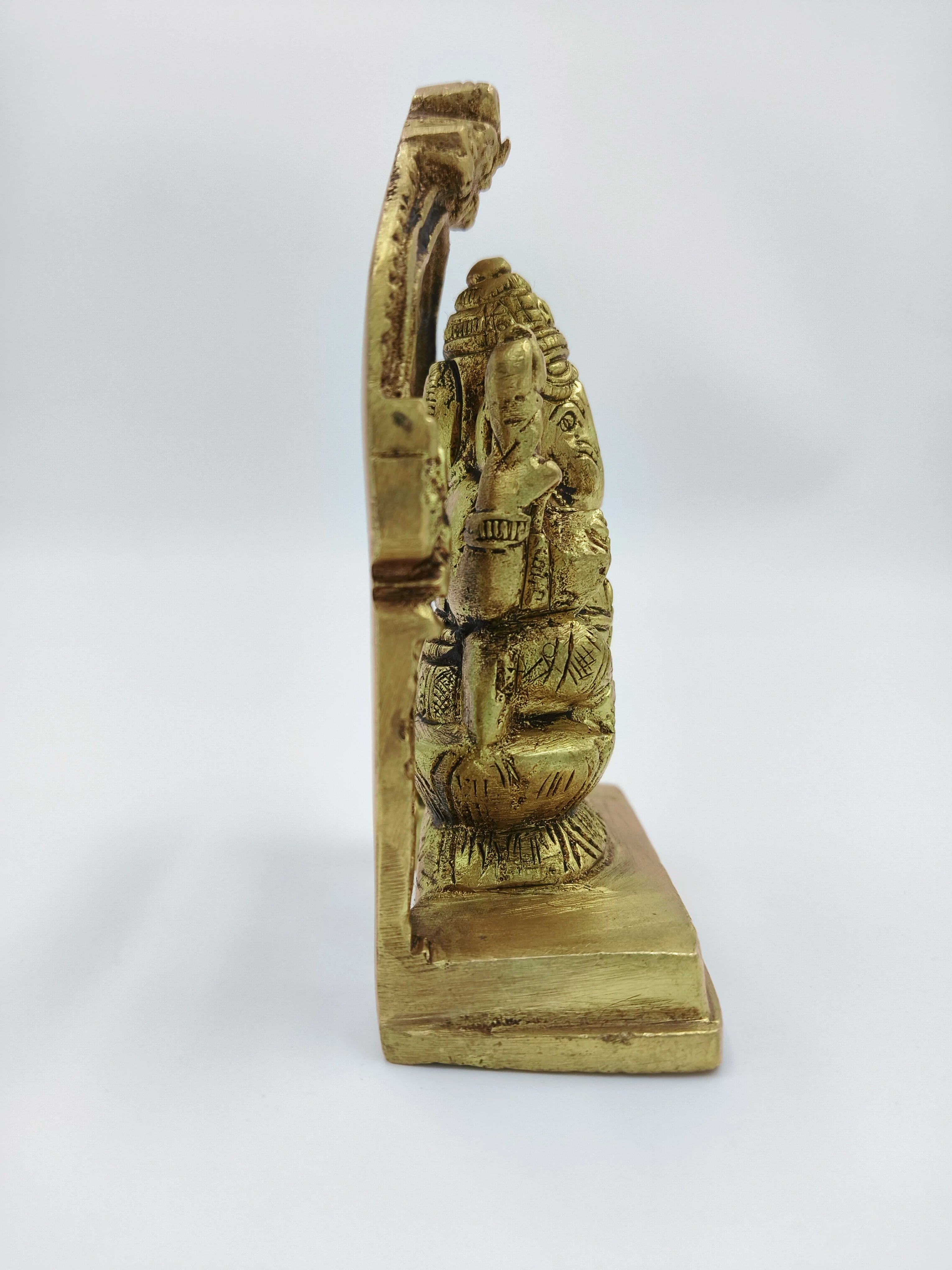 Side view of small brass Ganesh sculpture with decorative arch